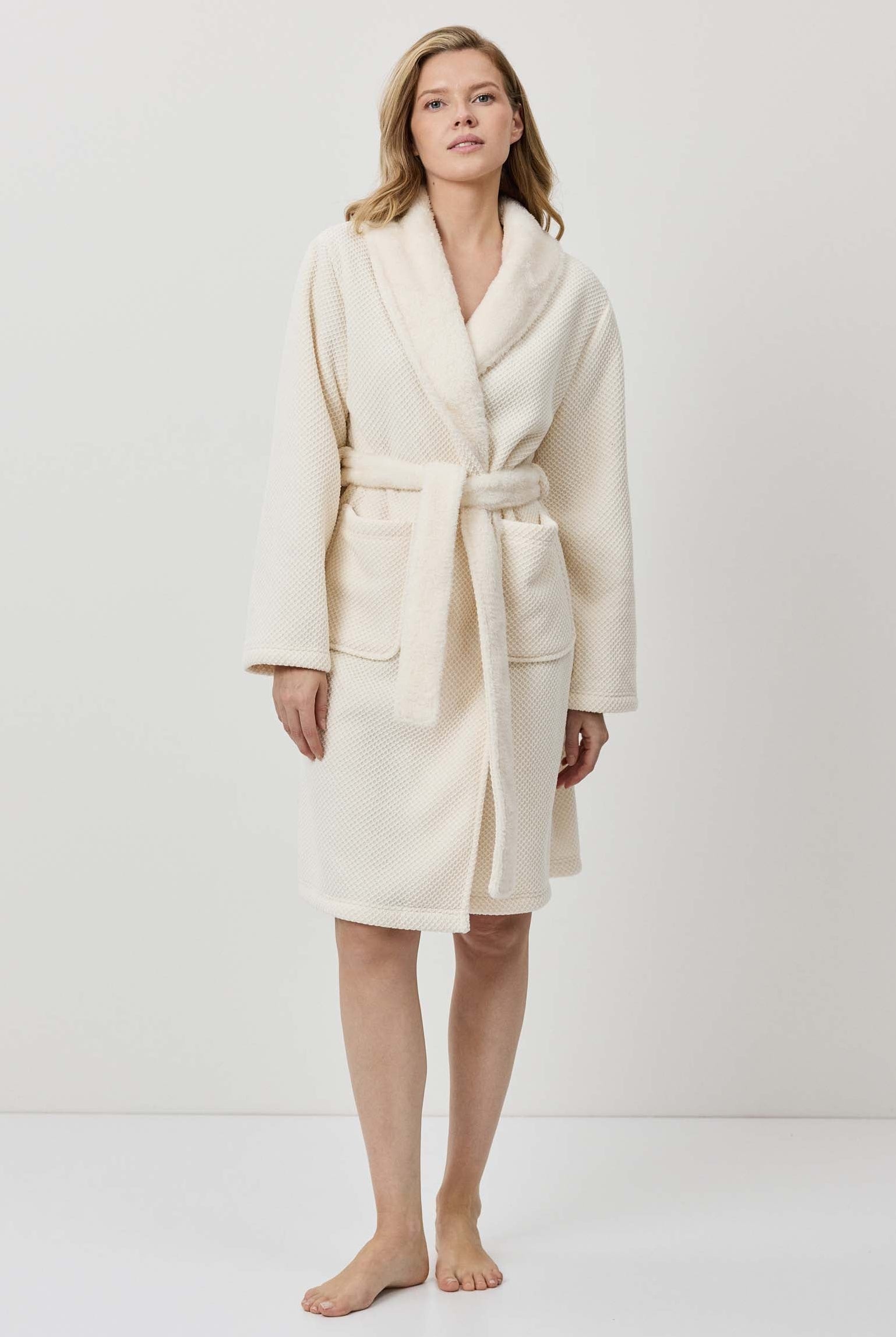 Woman wearing a cream-colored robe against a white background