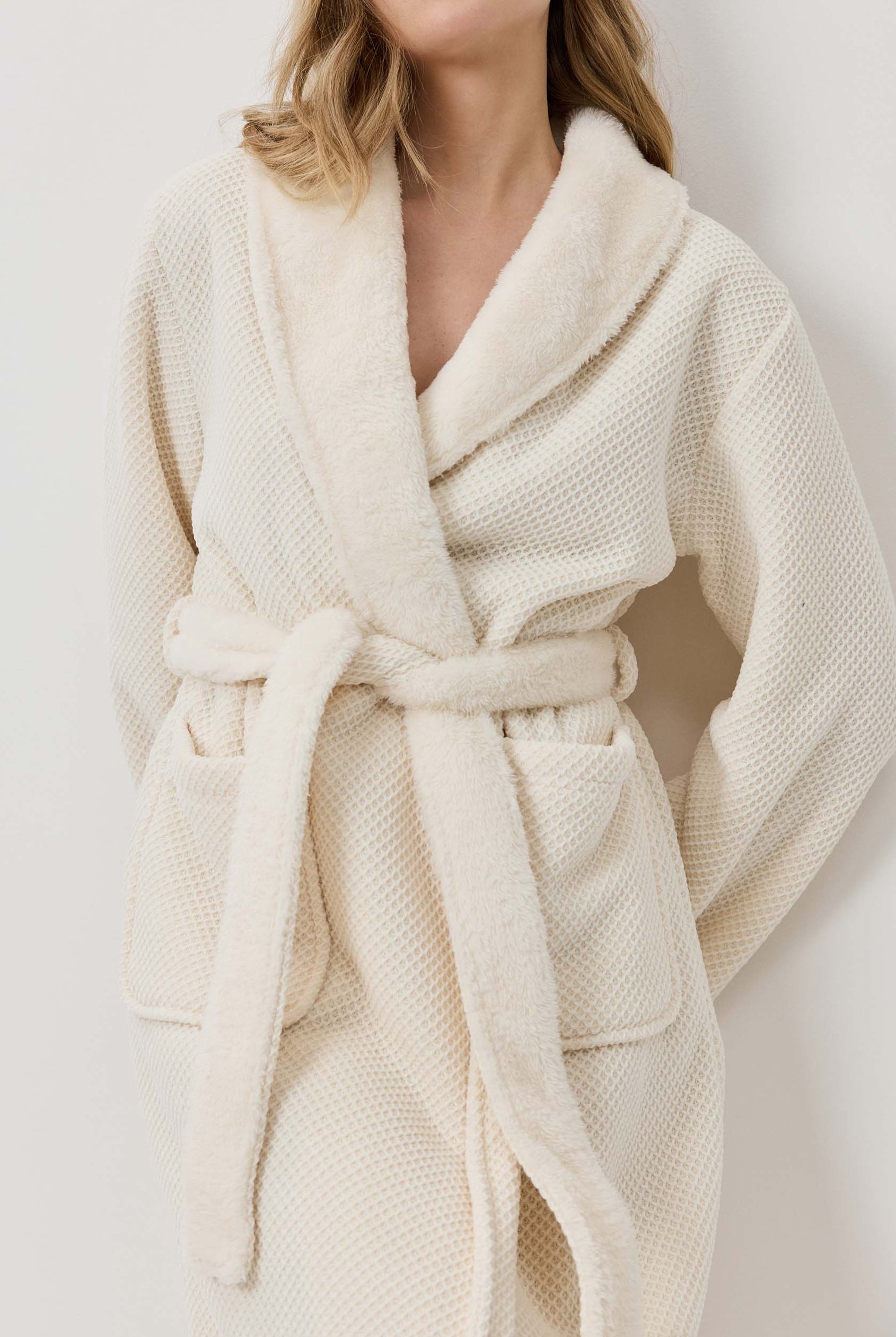 Woman wearing a cream-colored robe against a white background