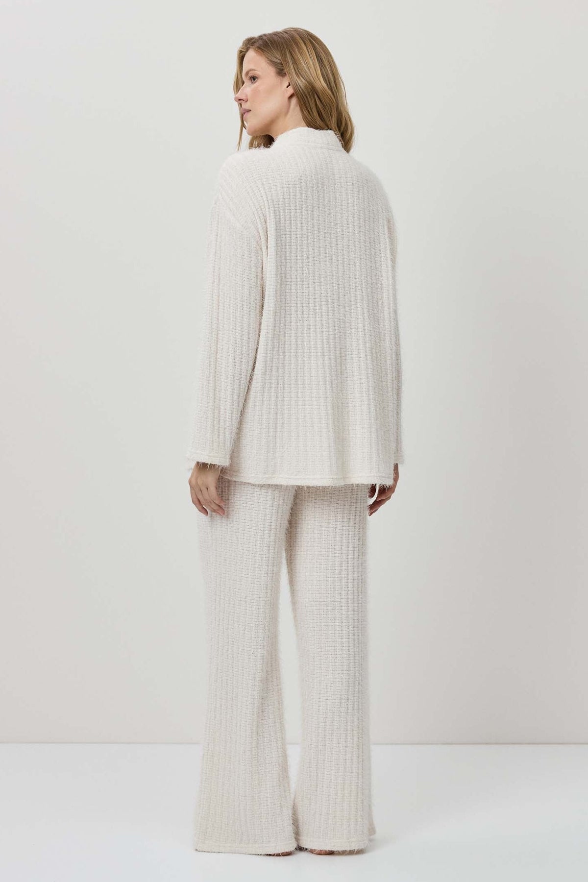 Woman wearing a white ribbed knit outfit against a plain background