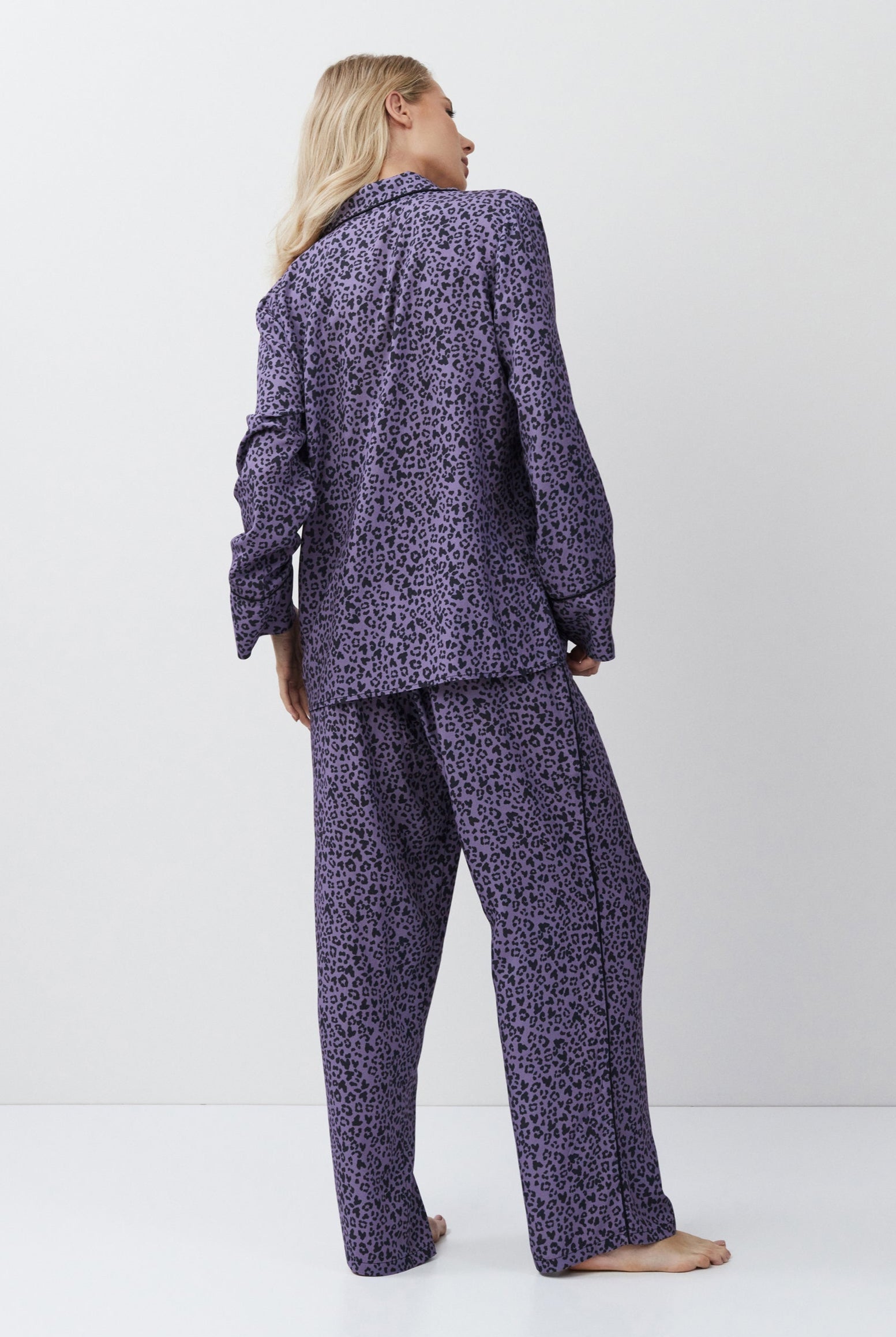 Person wearing a purple patterned pajama set on a white background