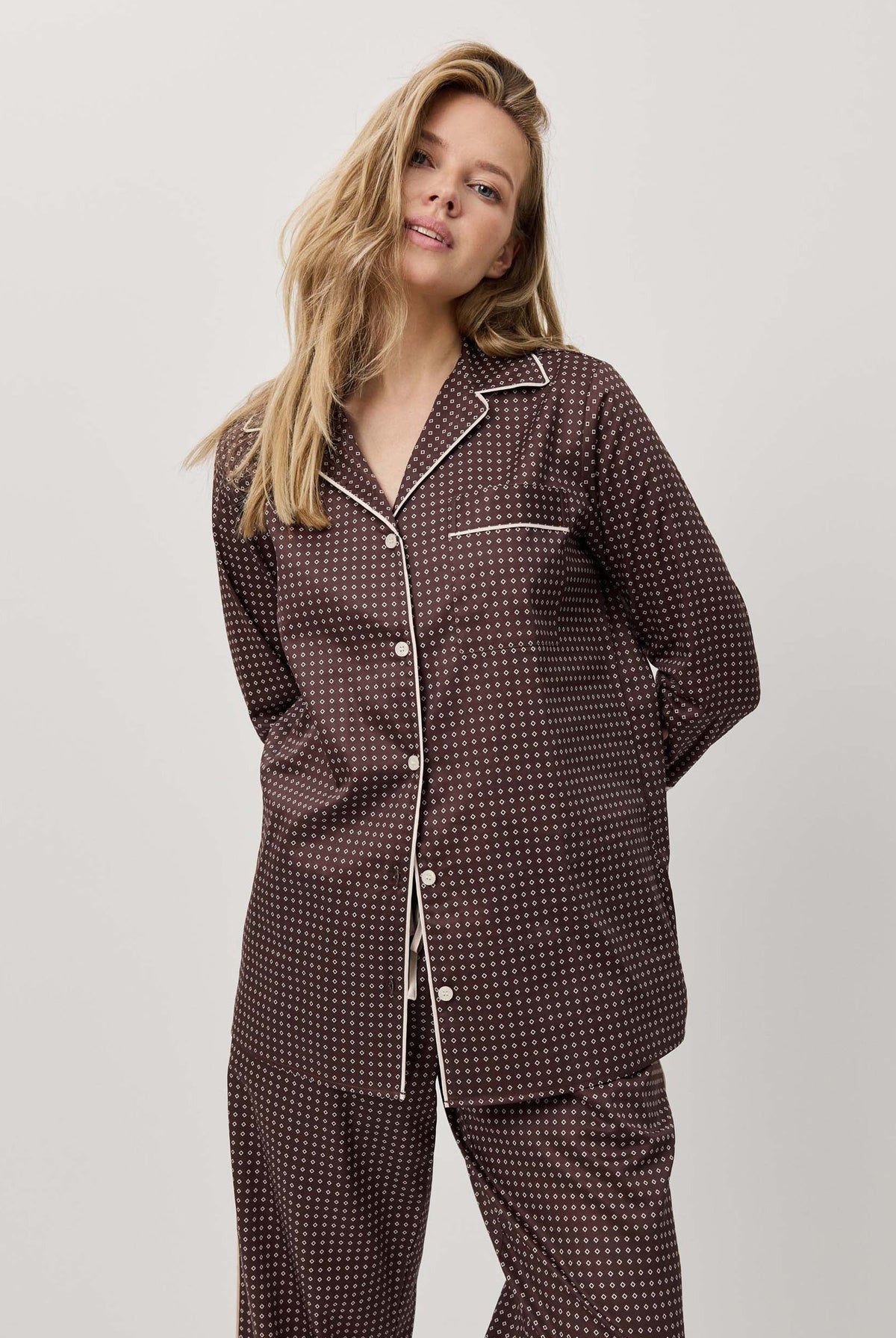 Woman wearing a dark patterned pajama set against a white background