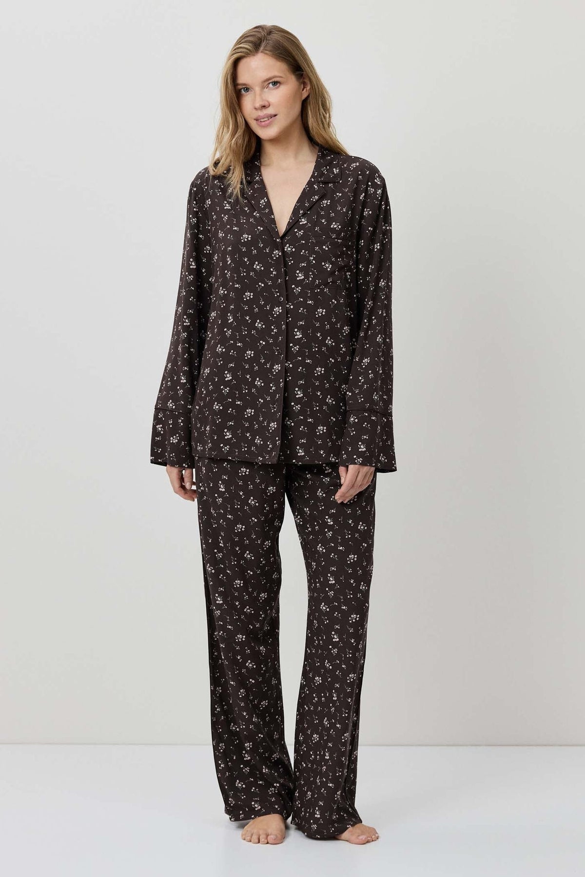 Woman wearing a black patterned pajama set on a white background