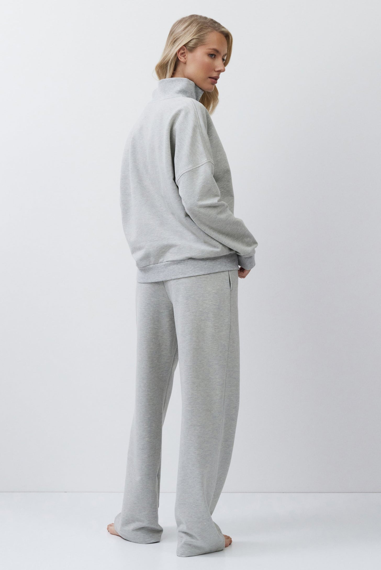 Woman wearing a gray tracksuit on a white background