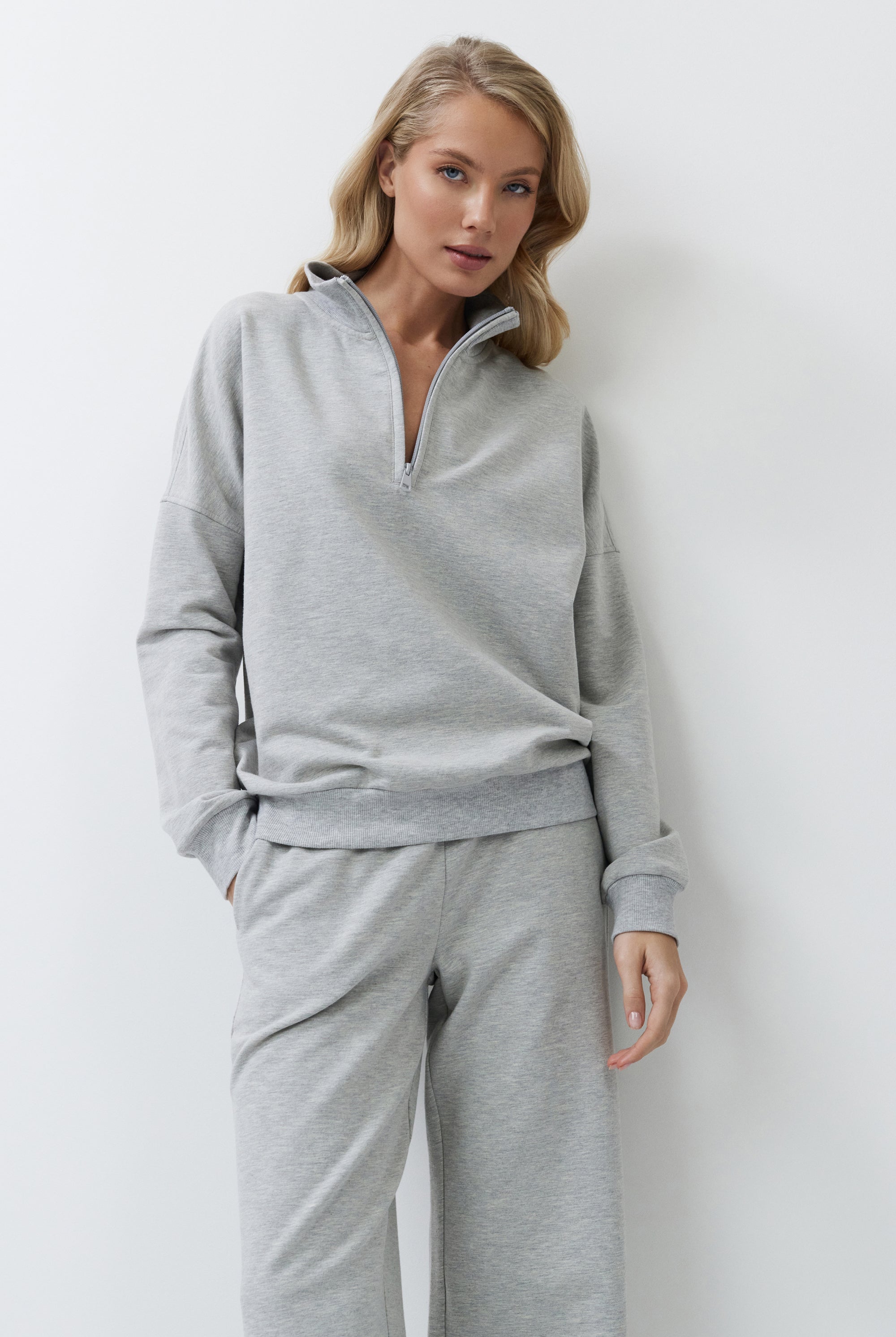Woman wearing a gray tracksuit against a white background