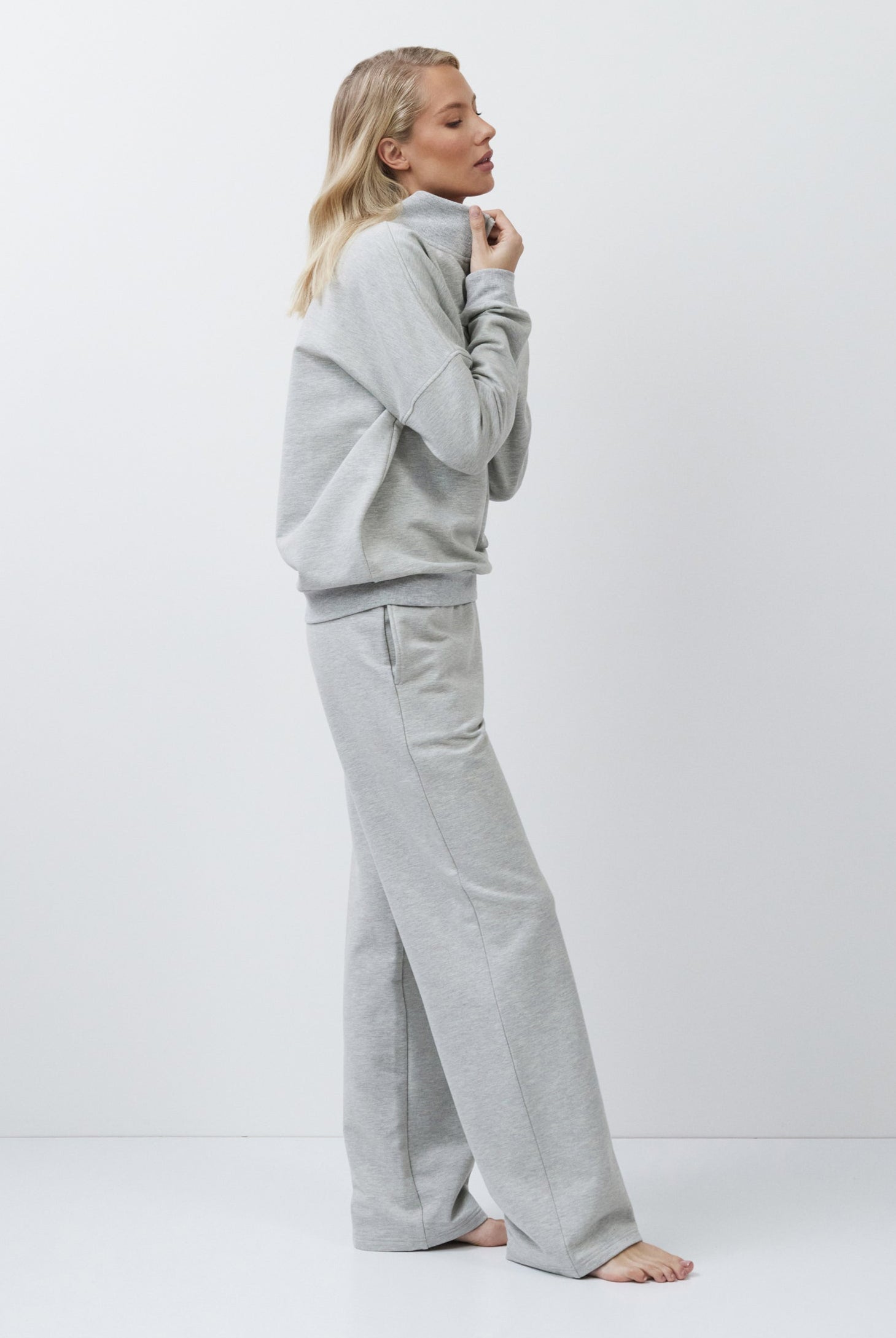 Person wearing a gray tracksuit on a white background