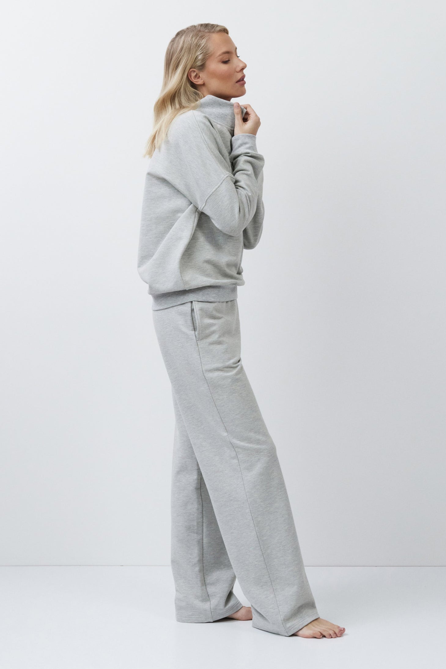 Person wearing a gray tracksuit on a white background