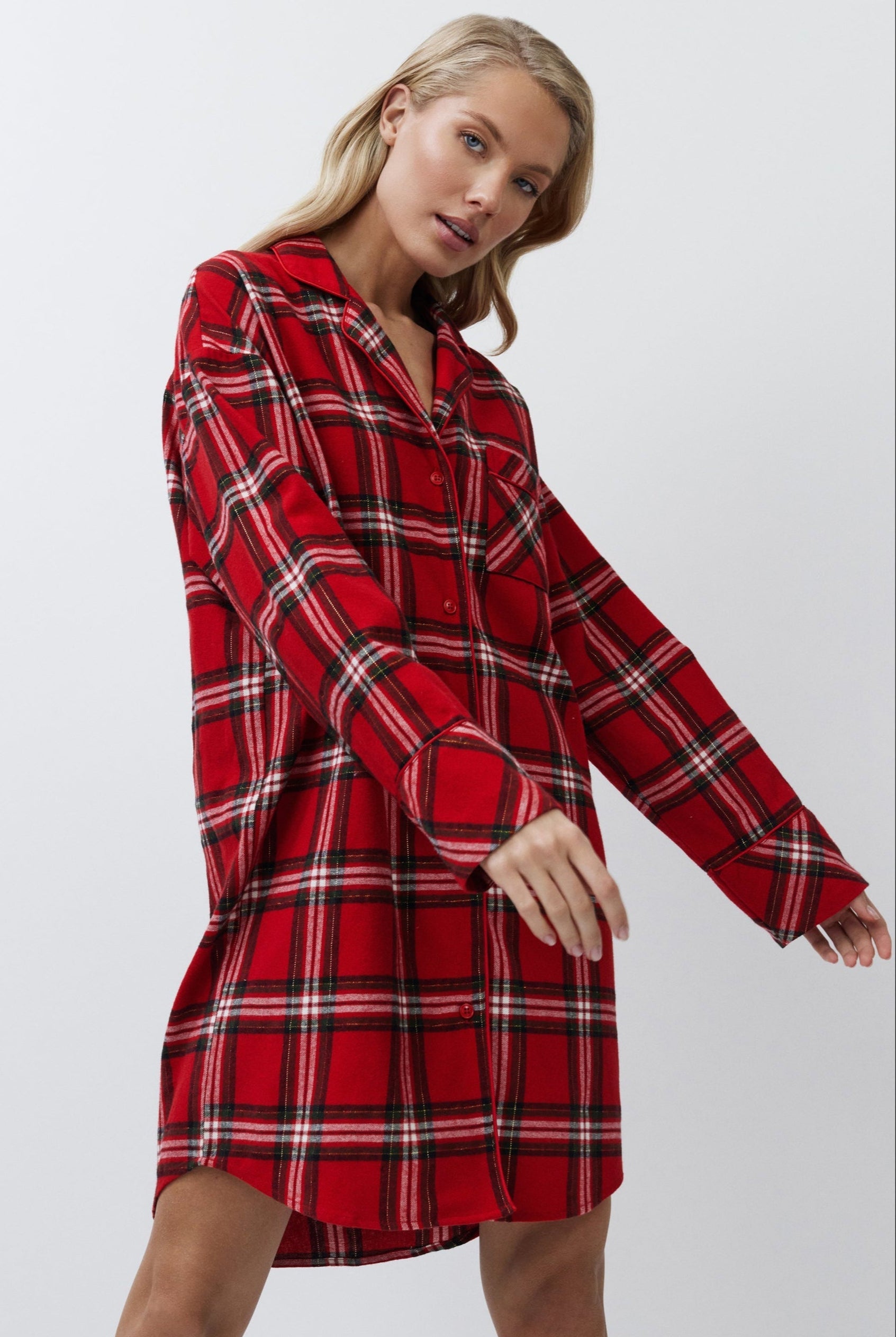 Woman wearing a red plaid shirt dress against a white background