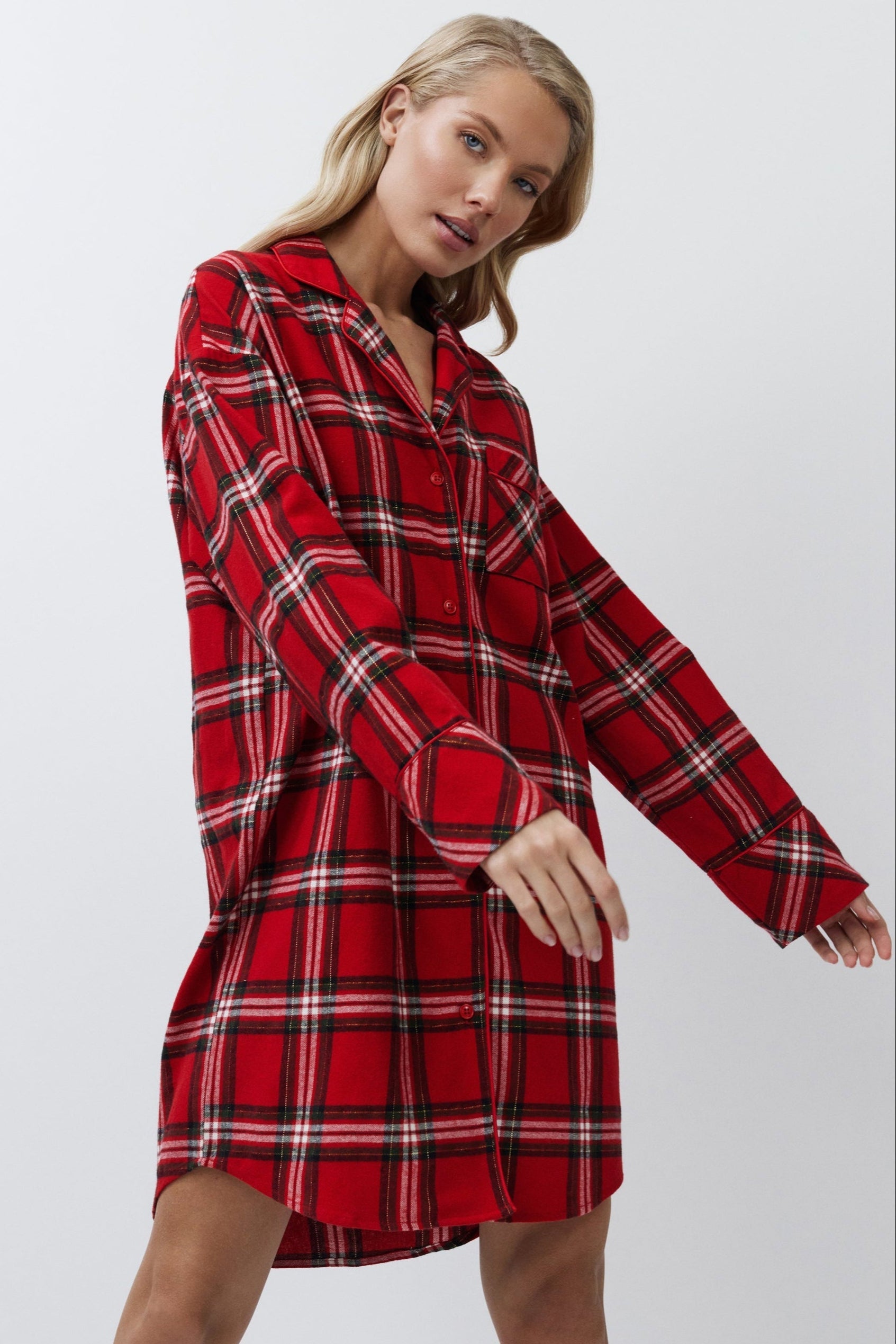 Woman wearing a red plaid shirt dress against a white background