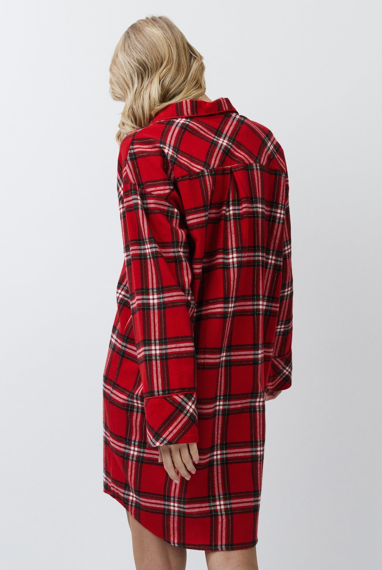 Person wearing a red plaid shirt dress against a white background