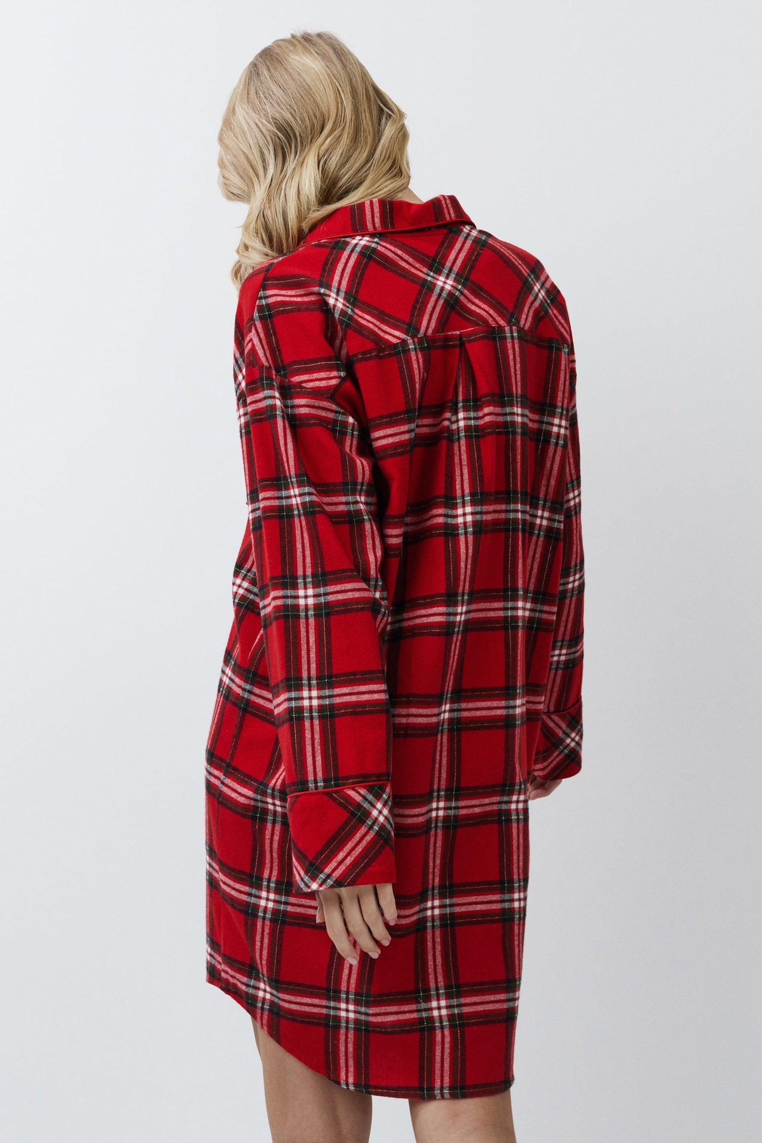 Person wearing a red plaid shirt dress against a white background