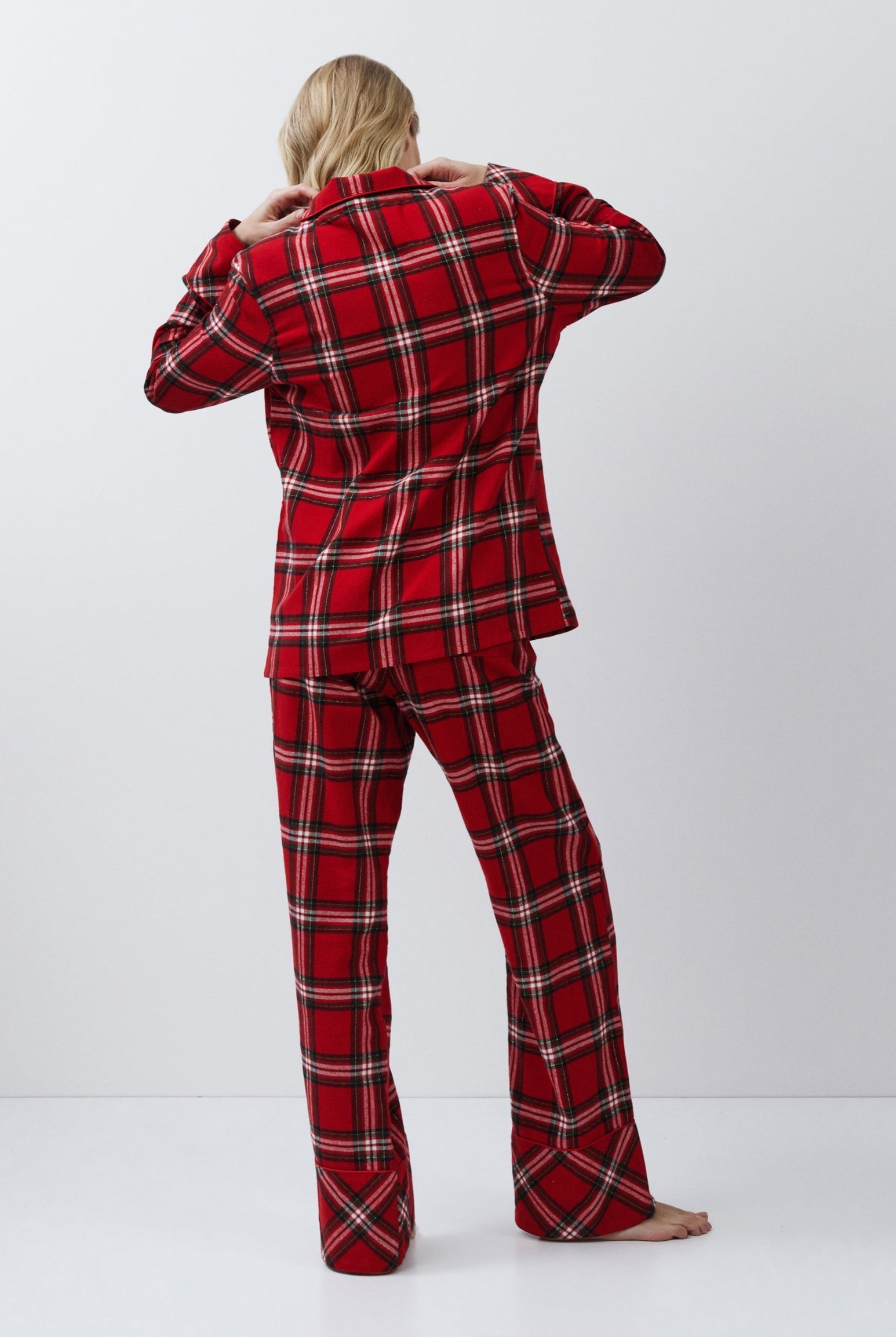 Person wearing a red plaid pajama set on a white background