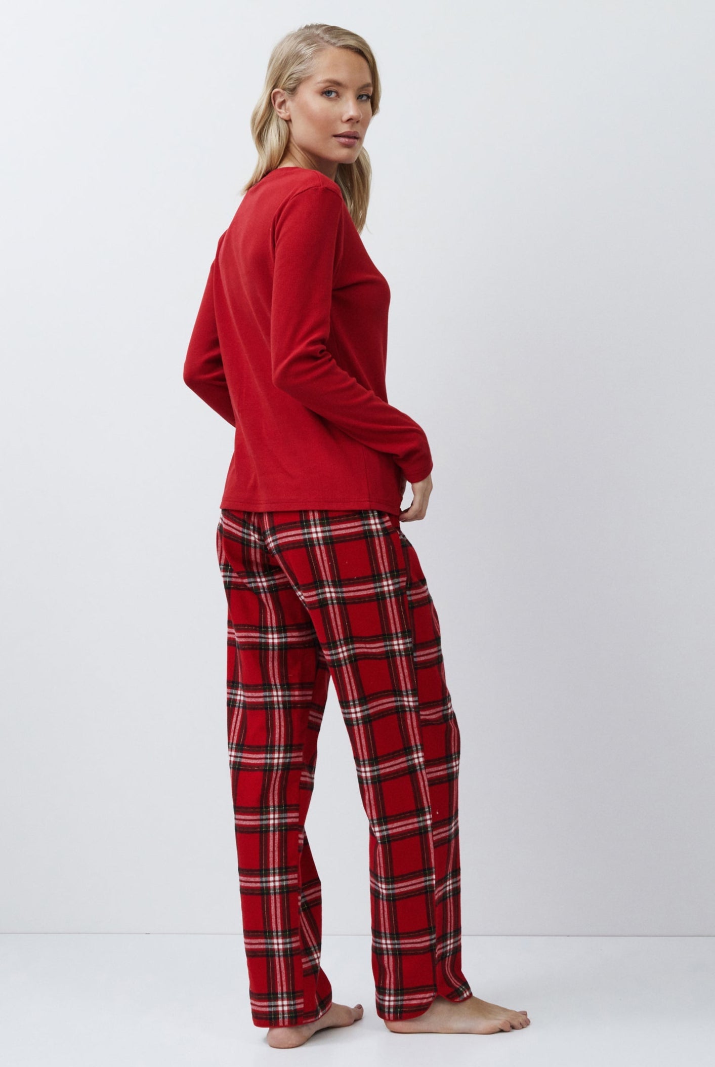 Person wearing a red top and plaid pants on a white background