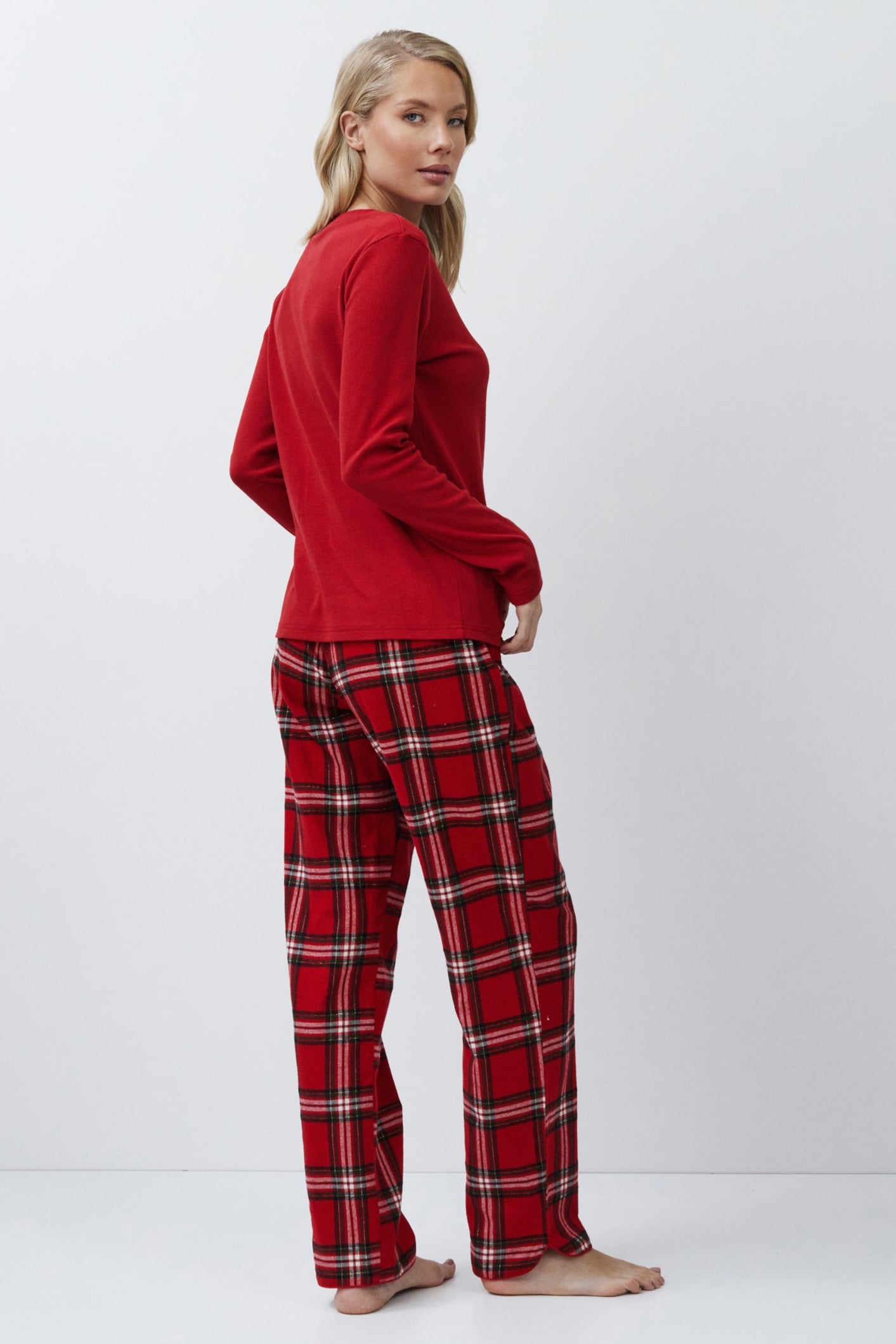 Person wearing a red top and plaid pants on a white background