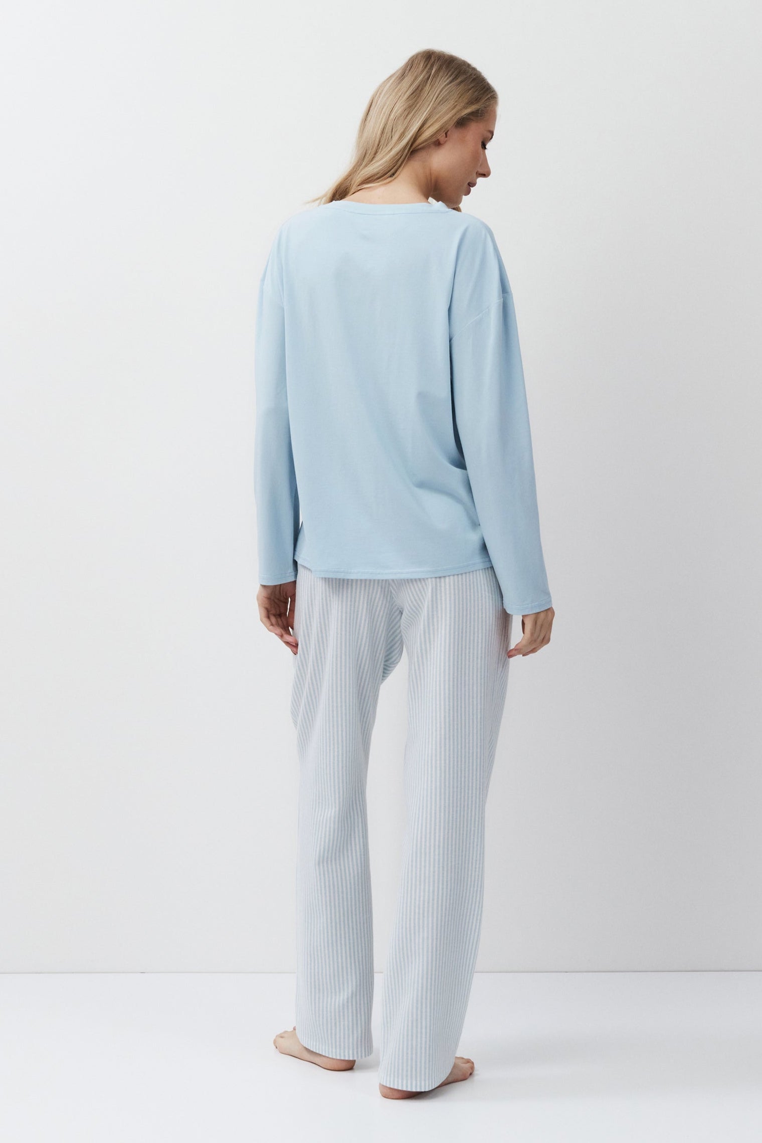 Woman wearing a light blue top and pants on a white background