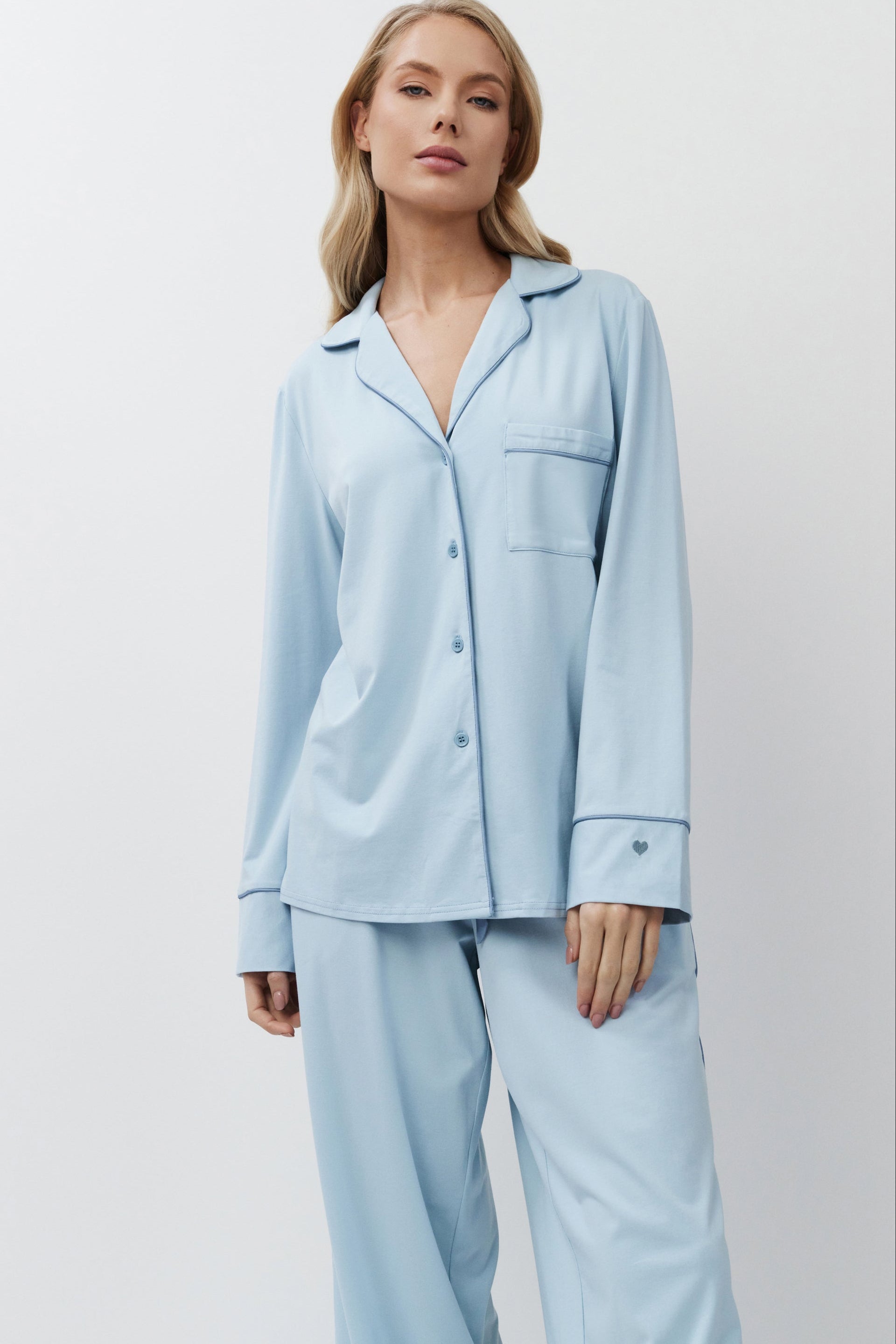 Woman wearing light blue pajamas against a plain background