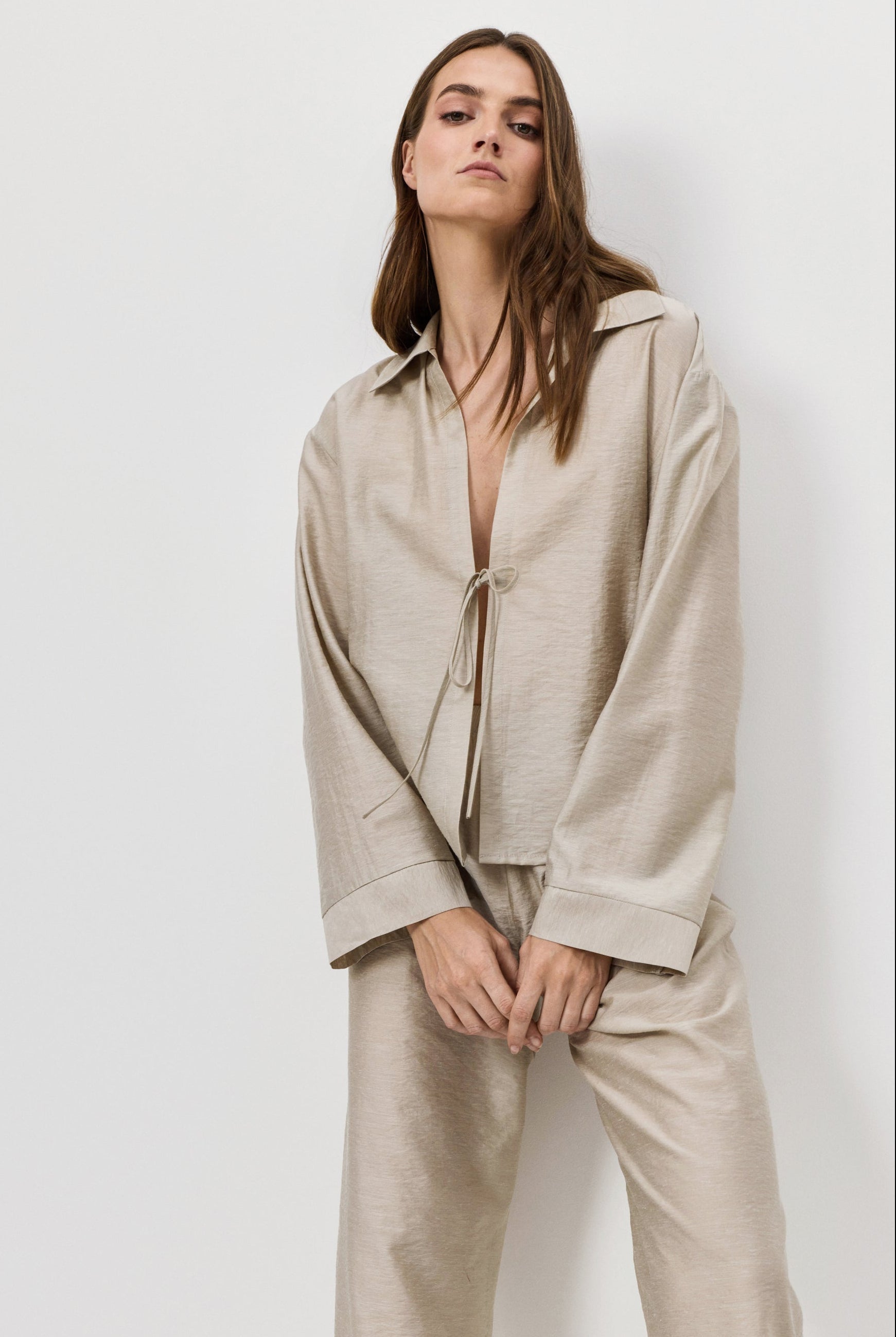 Woman wearing a beige shirt and pants against a white background