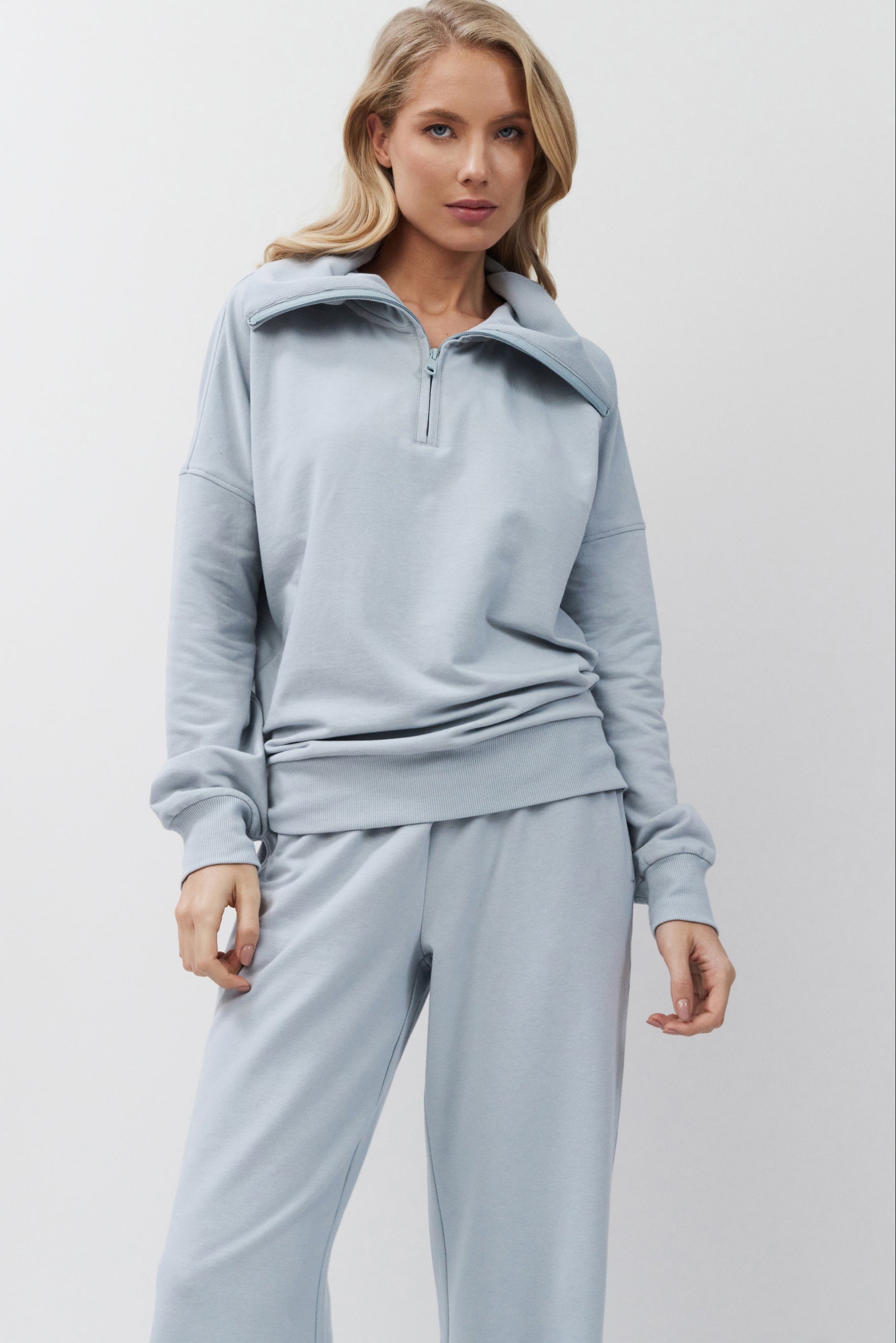 Woman wearing a light blue tracksuit against a plain background
