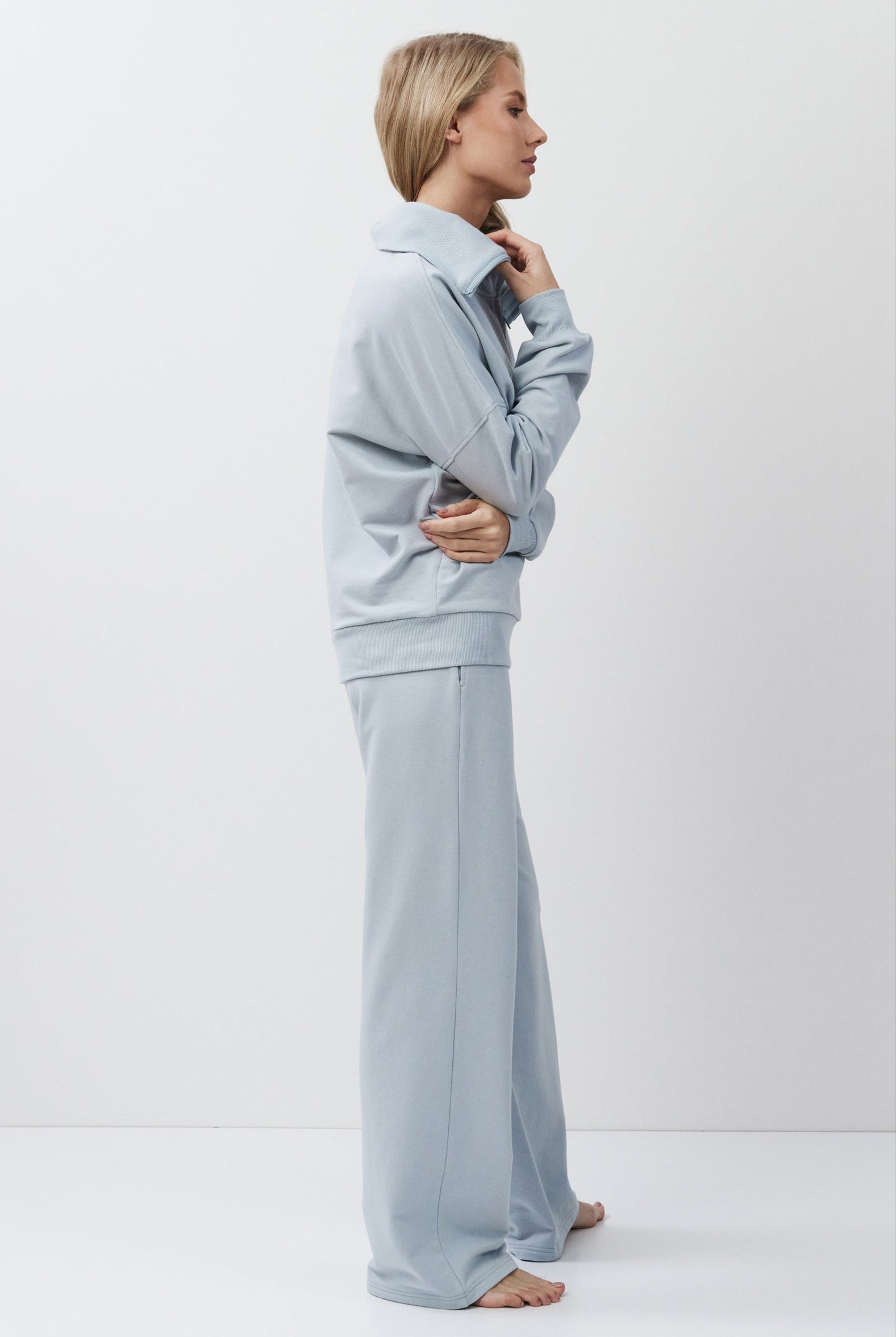 Woman wearing a light blue outfit standing against a white background