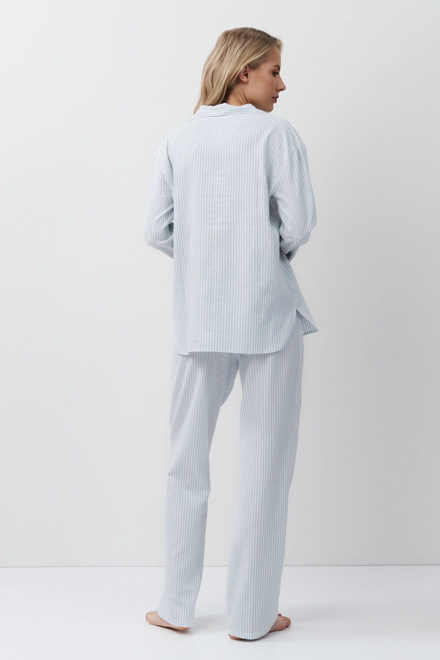 Woman wearing a light blue outfit standing against a white background