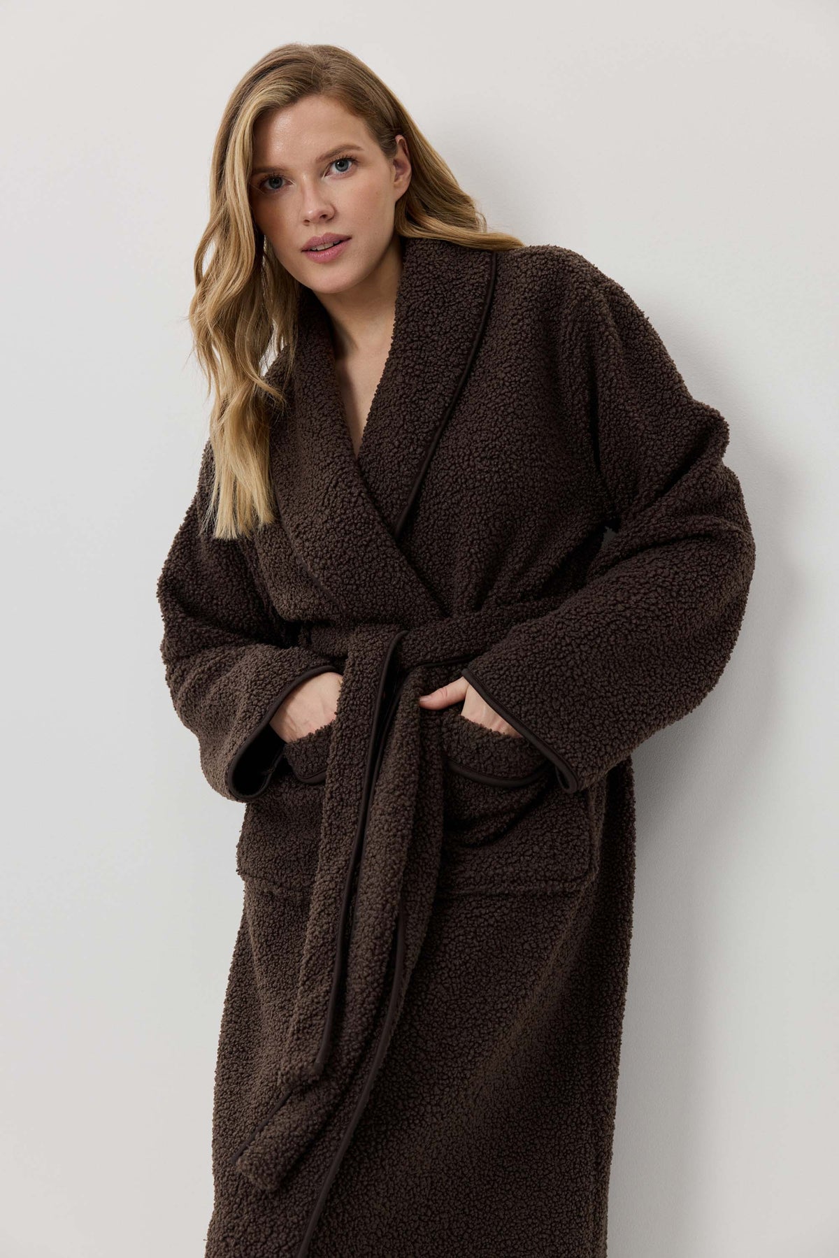 Woman wearing a brown robe against a white background