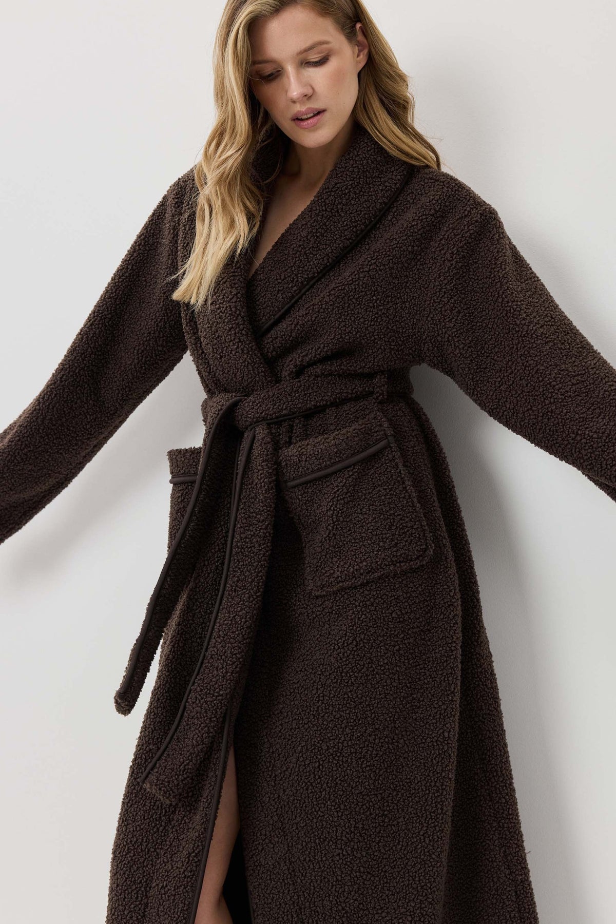 Woman wearing a brown robe against a white background