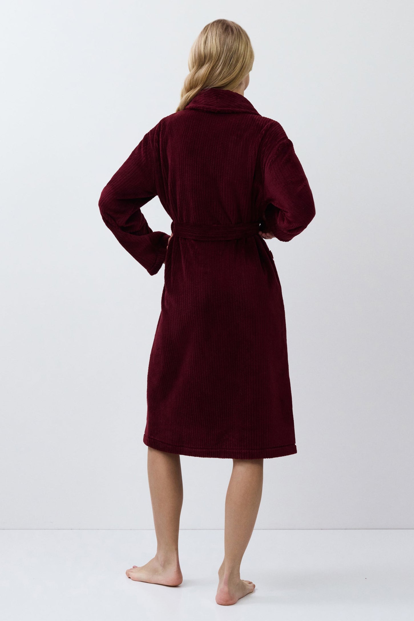 Person wearing a burgundy robe against a white background