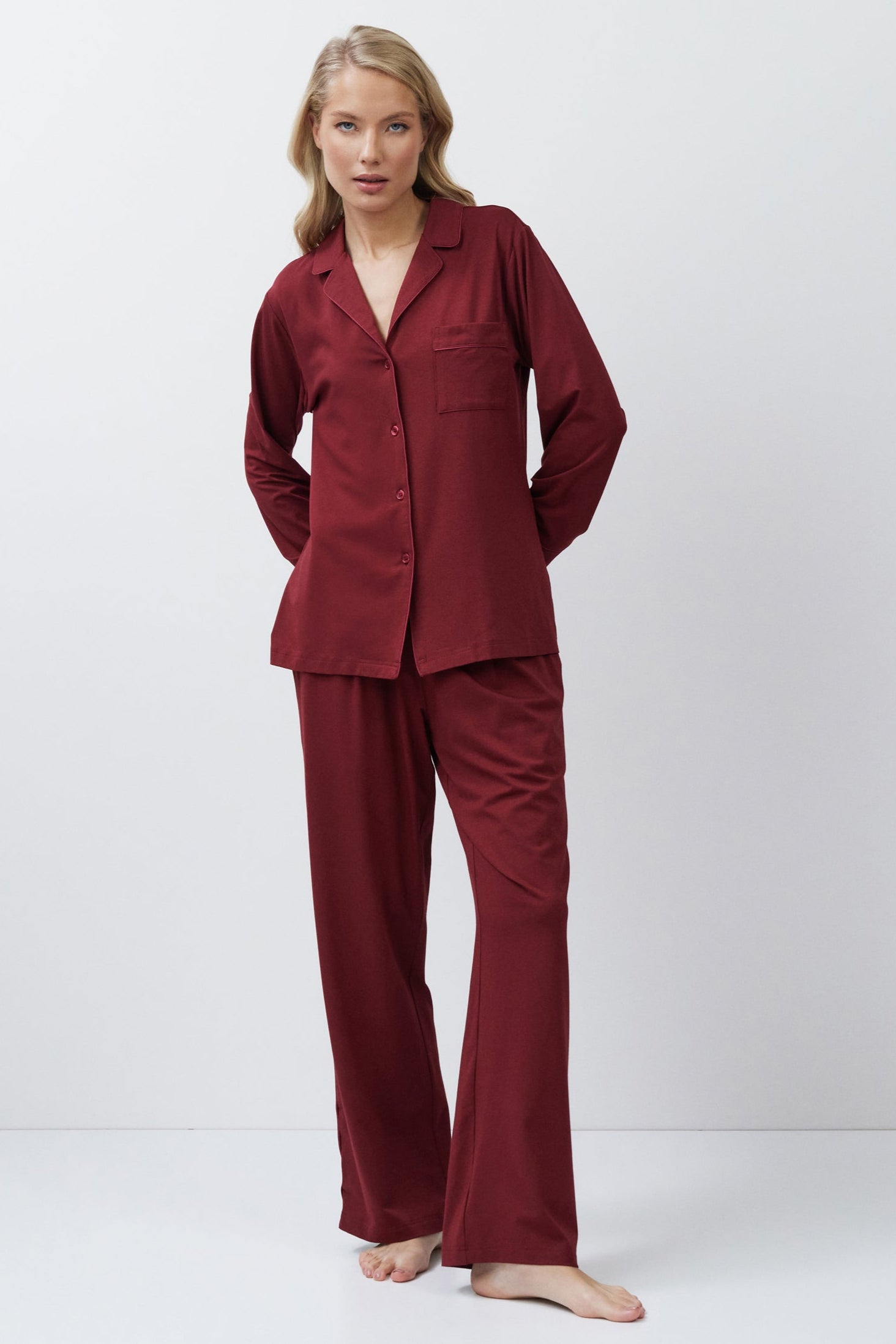 Woman wearing a burgundy pajama set against a white background
