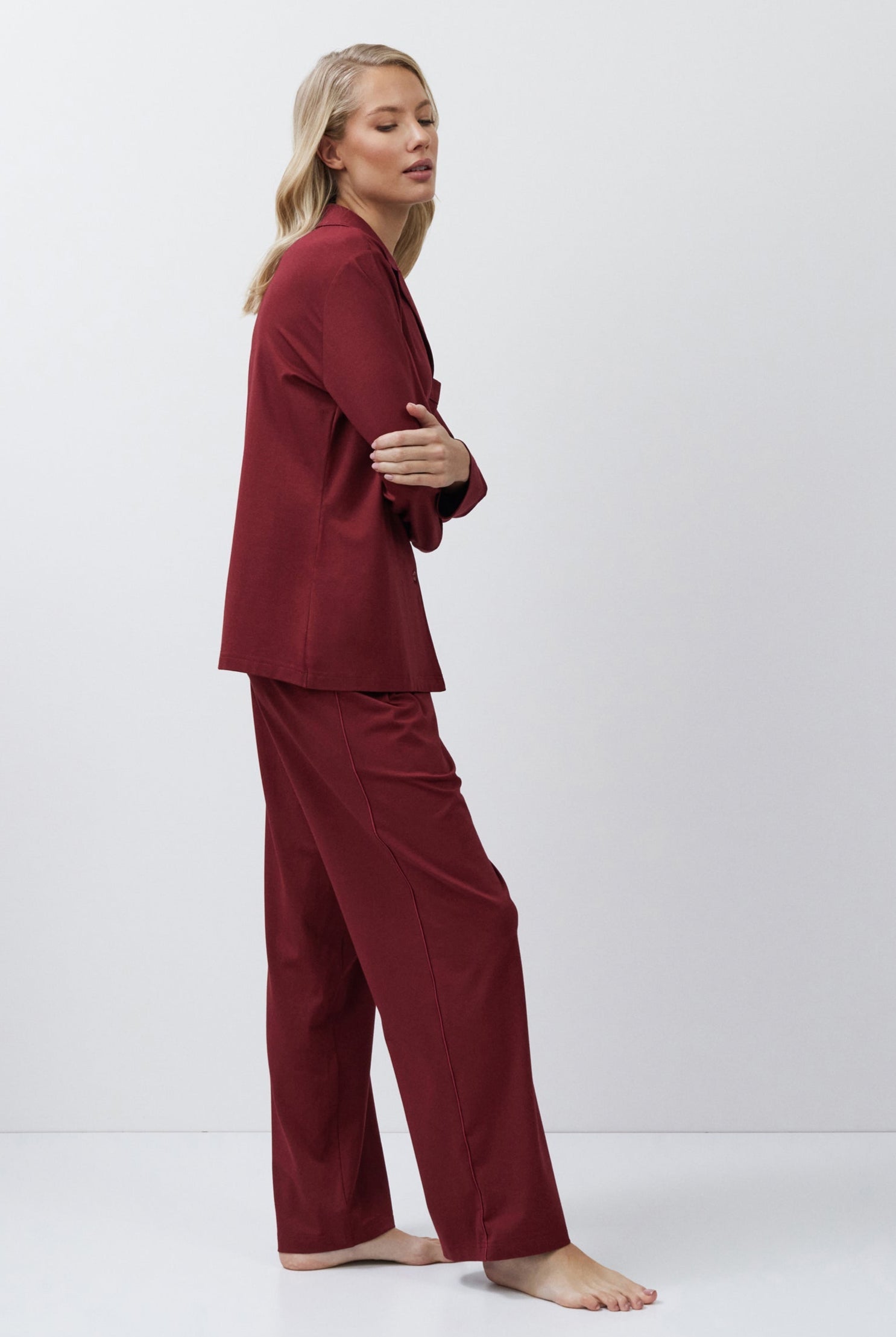 Woman wearing burgundy pajama set on a white background