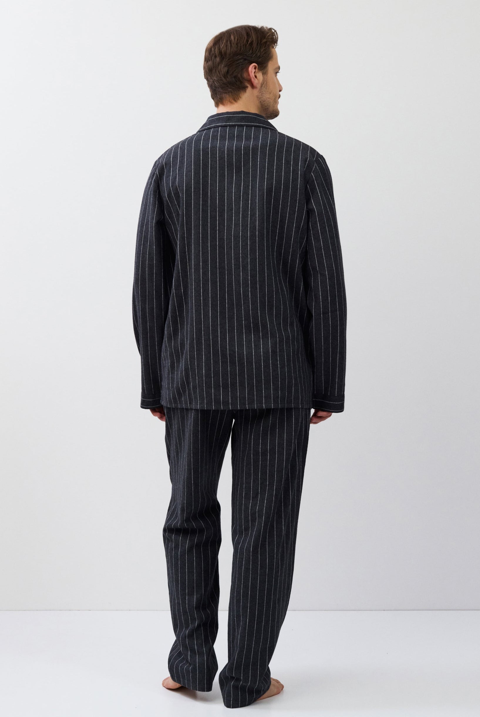 Man wearing a pinstripe pajama set on a white background