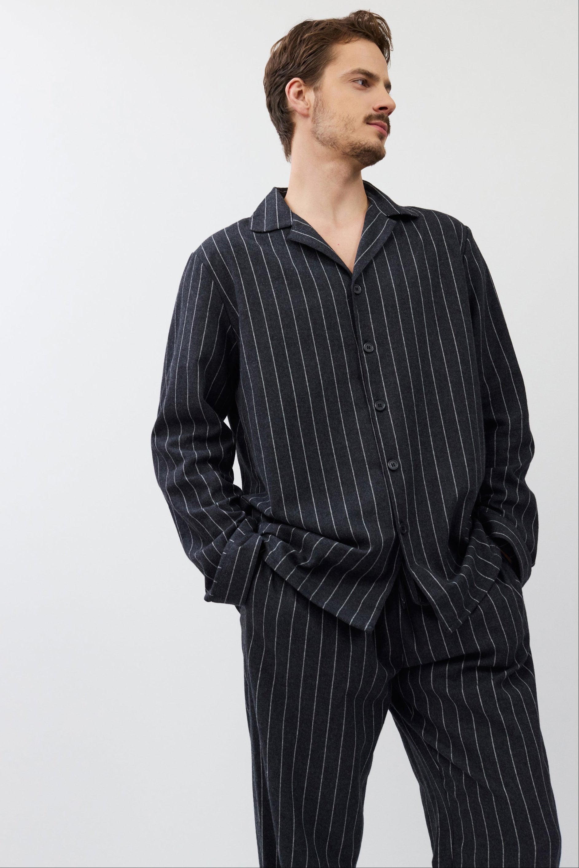 Man wearing a dark pinstripe pajama set against a white background