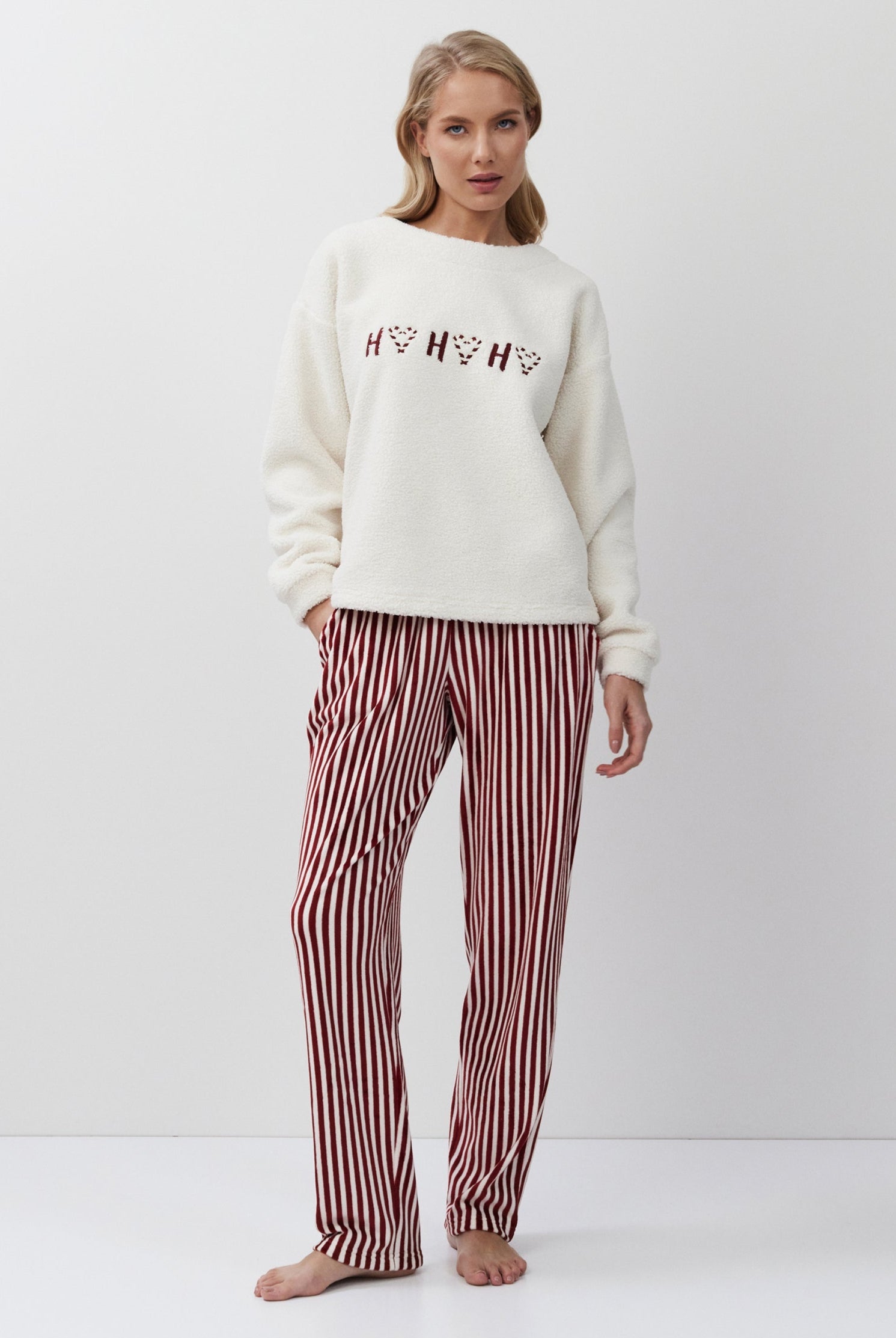 Woman wearing a white sweatshirt with text and red striped pants on a white background