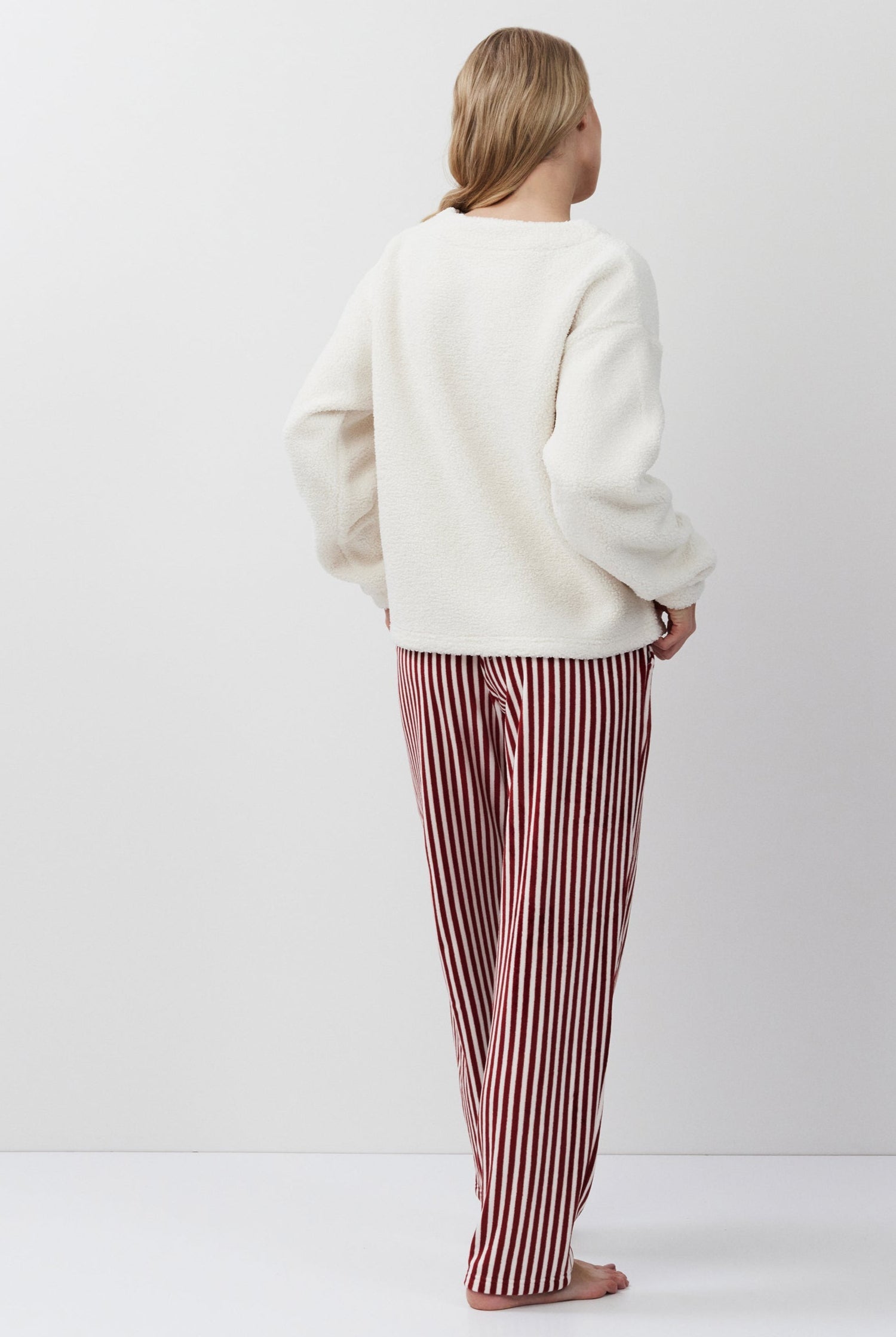 Person wearing a white sweater and red striped pants on a white background