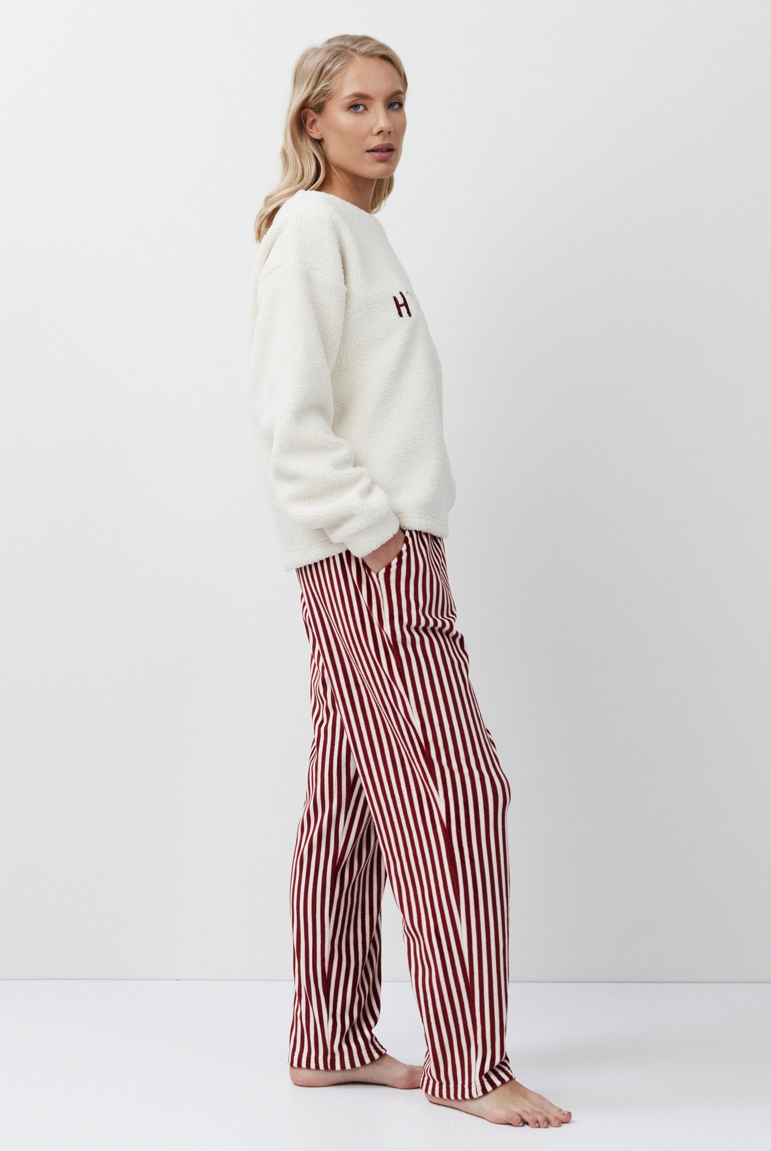 Woman wearing a white sweater and red striped pants on a white background