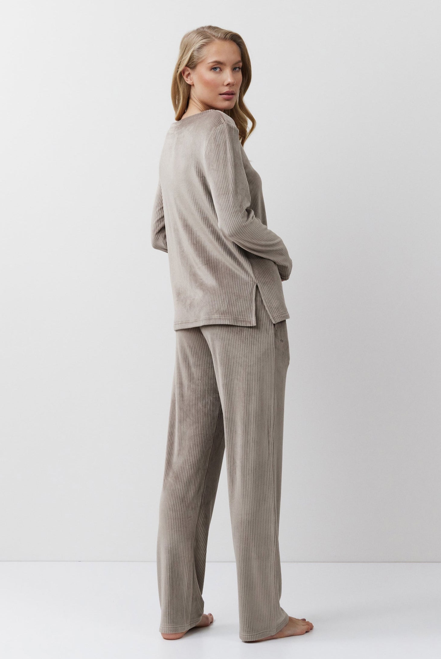 Woman wearing a capucine outfit standing against a white background