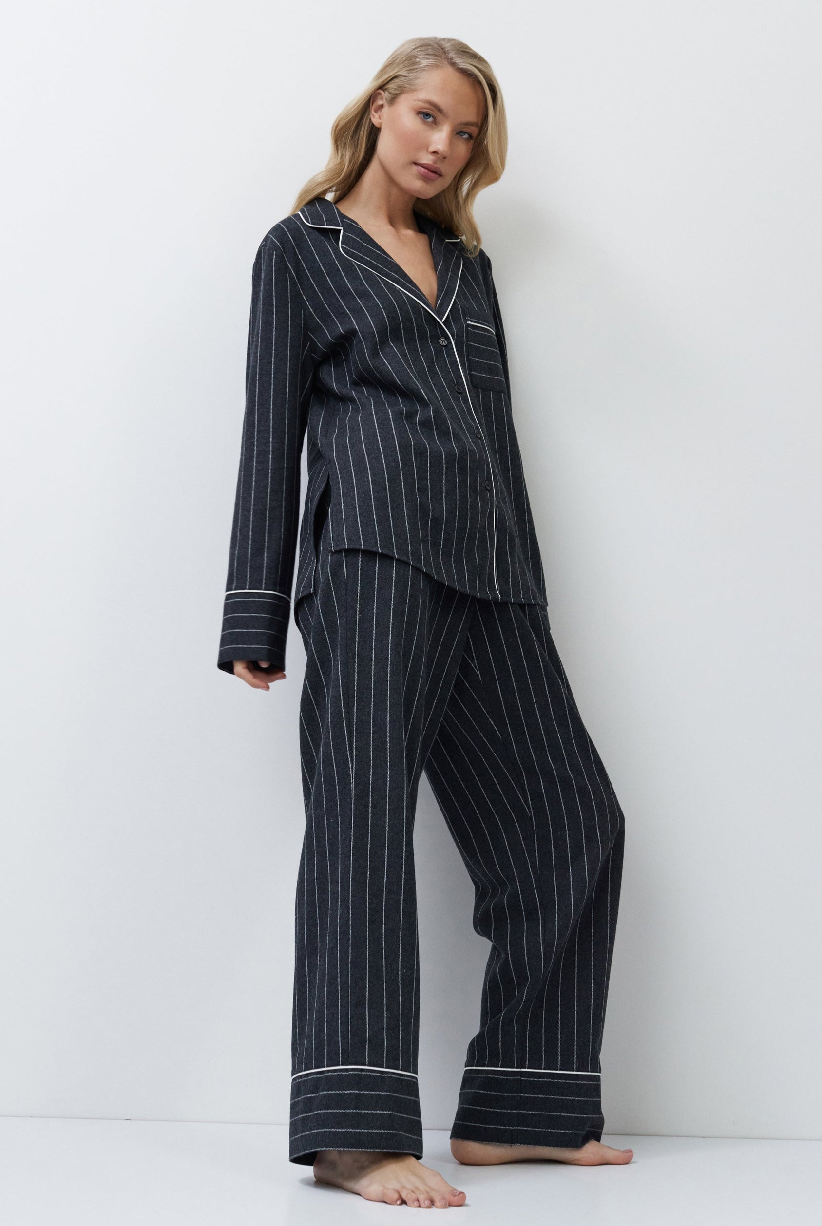 Woman wearing a gray pinstripe pajama set against a white background
