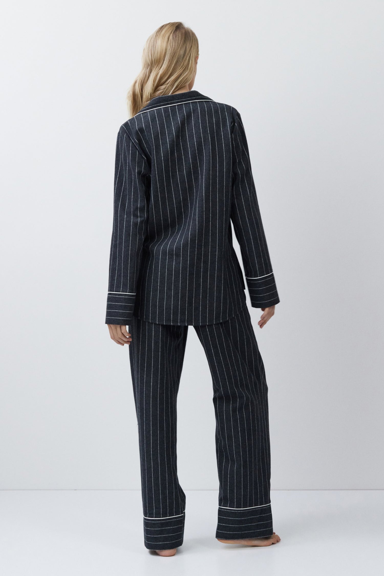Person wearing a gray pinstripe pajama set on a white background