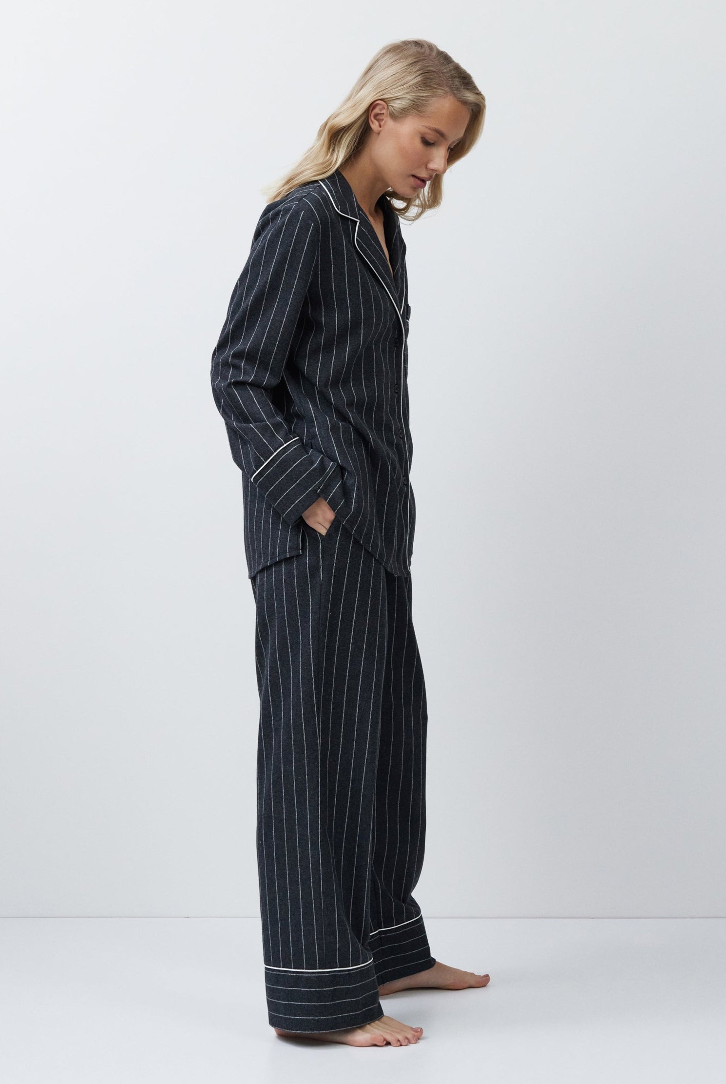 Woman wearing a gray pinstripe pajama set on a white background