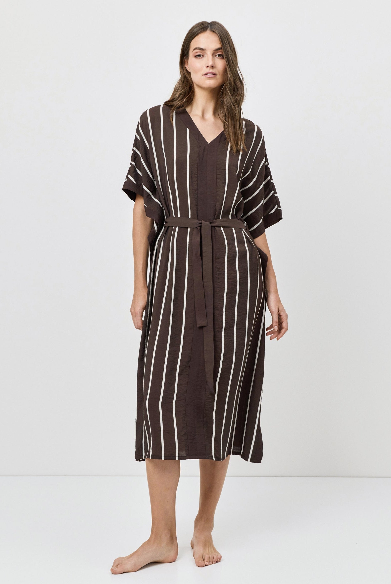 Woman wearing a brown and white striped dress on a white background