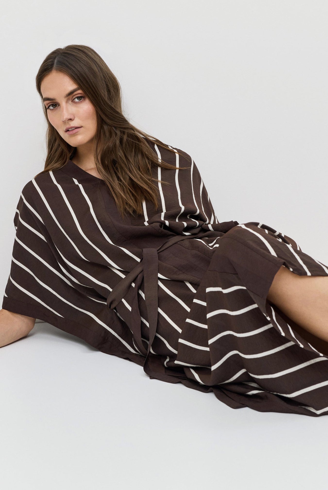 Woman wearing a brown and white striped dress on a white background