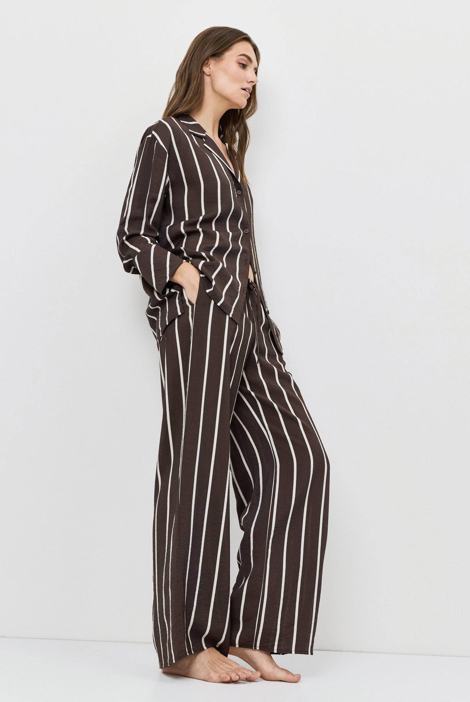 Woman wearing a brown and white striped resort wear set on a white background