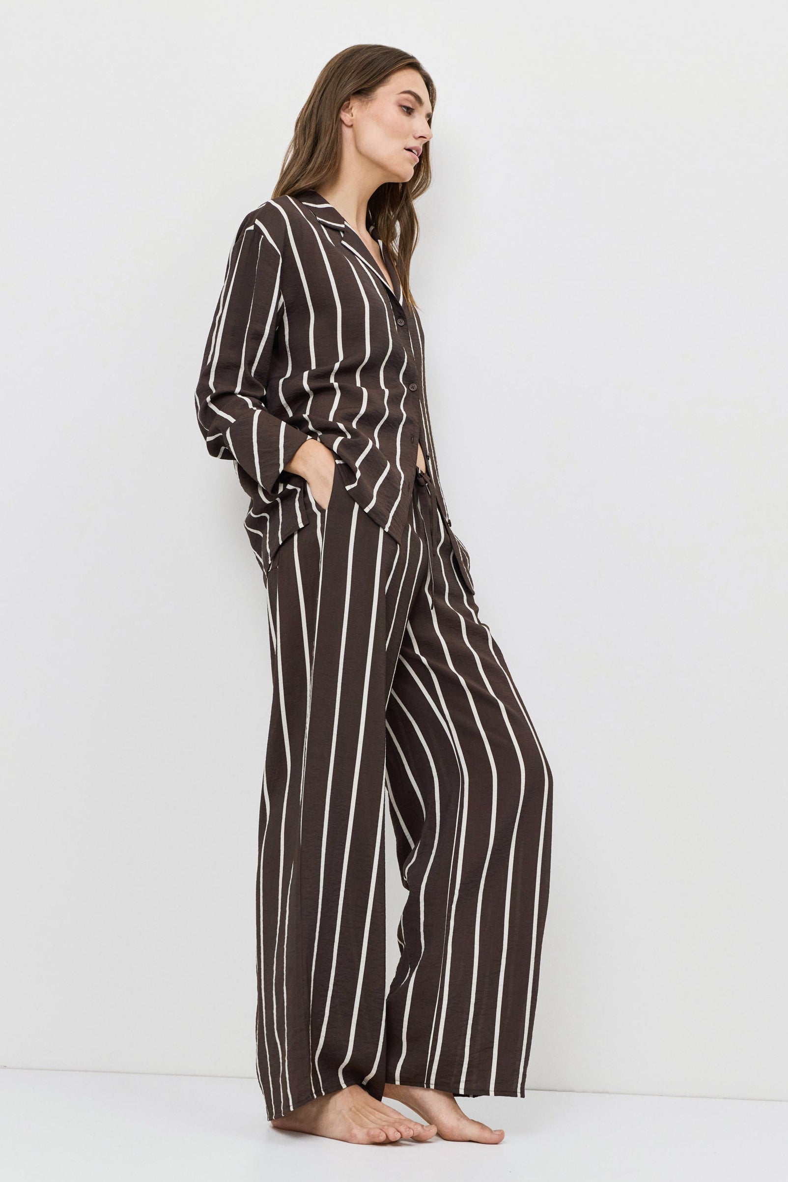 Woman wearing a brown and white striped resort wear set on a white background