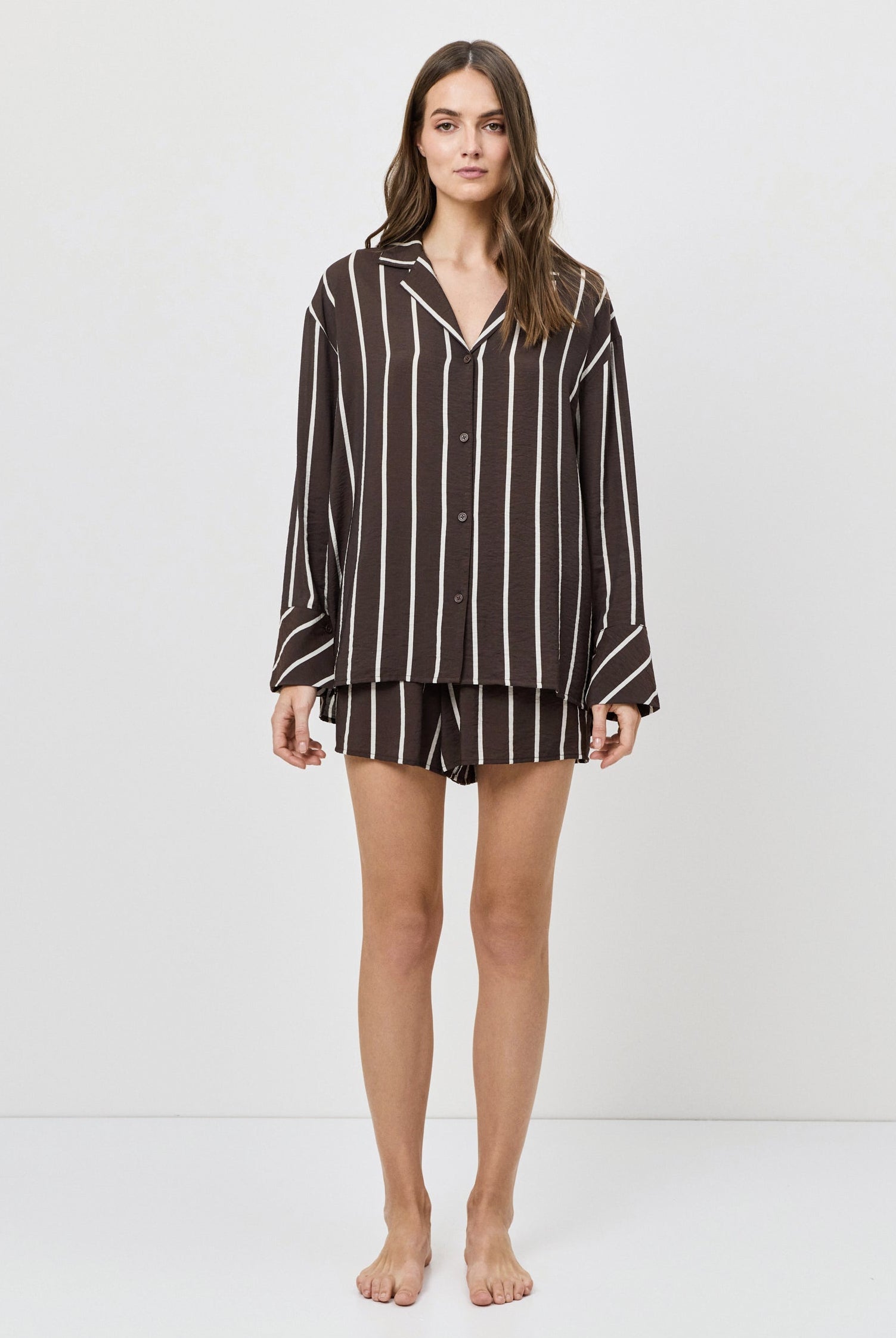 Woman wearing a brown and white striped shirt and shorts on a white background