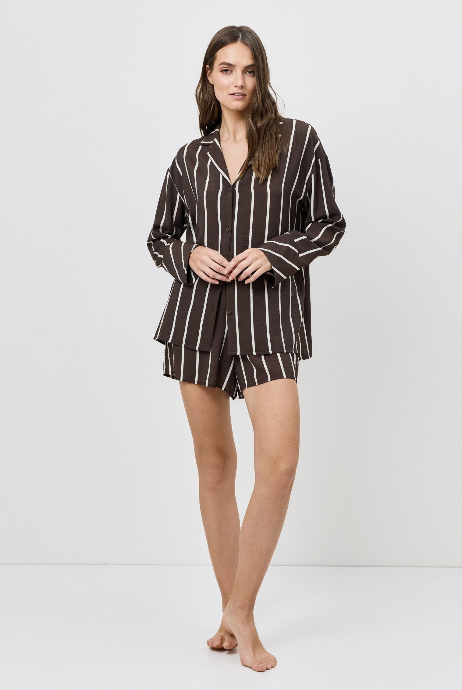 Woman wearing a brown and white striped resort wear set on a white background