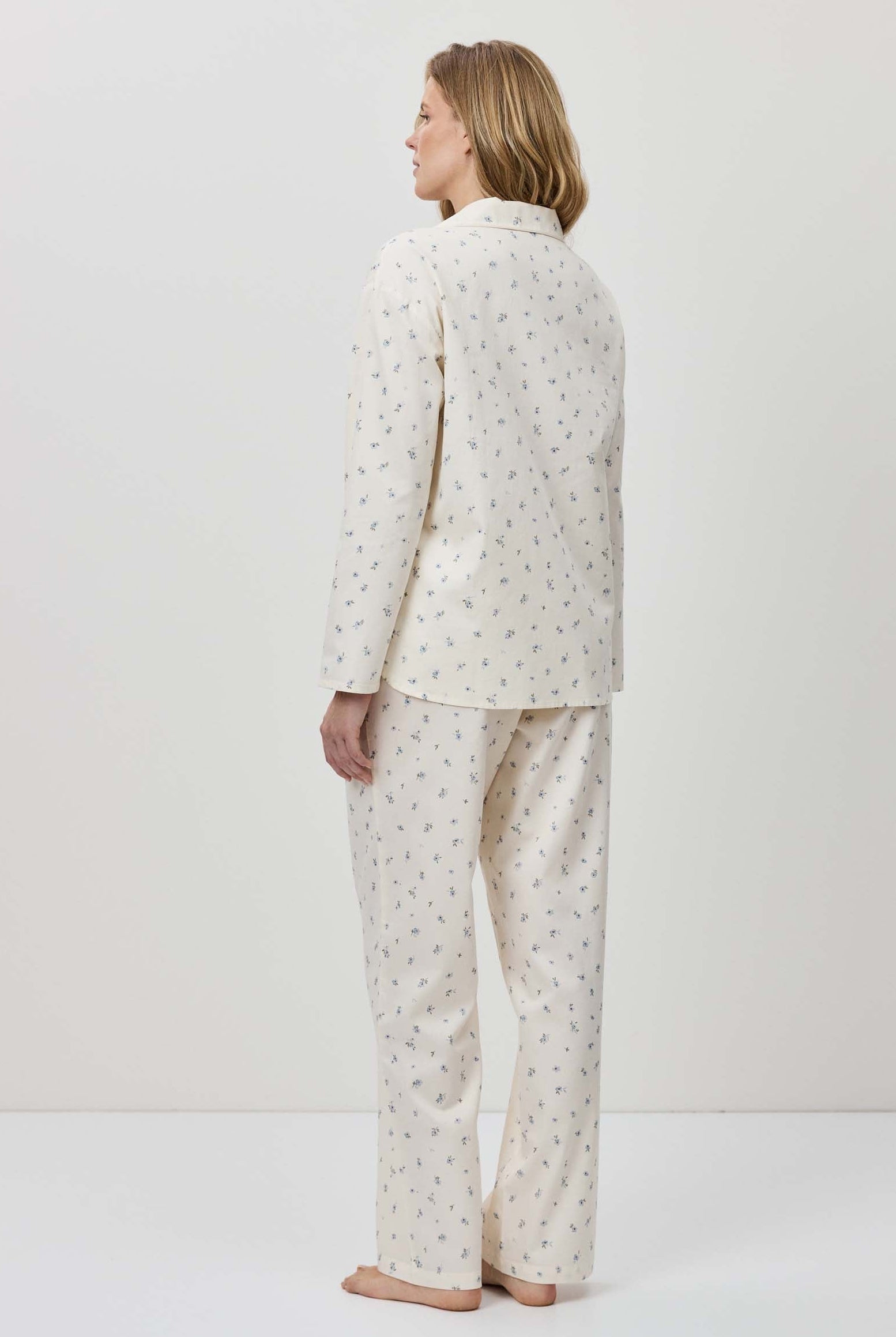 Person wearing a white pajama set with a subtle pattern on a plain background