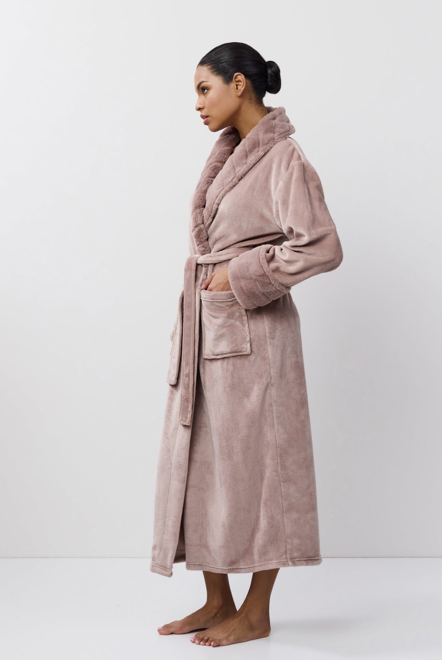 Woman wearing a long pink bathrobe against a white background
