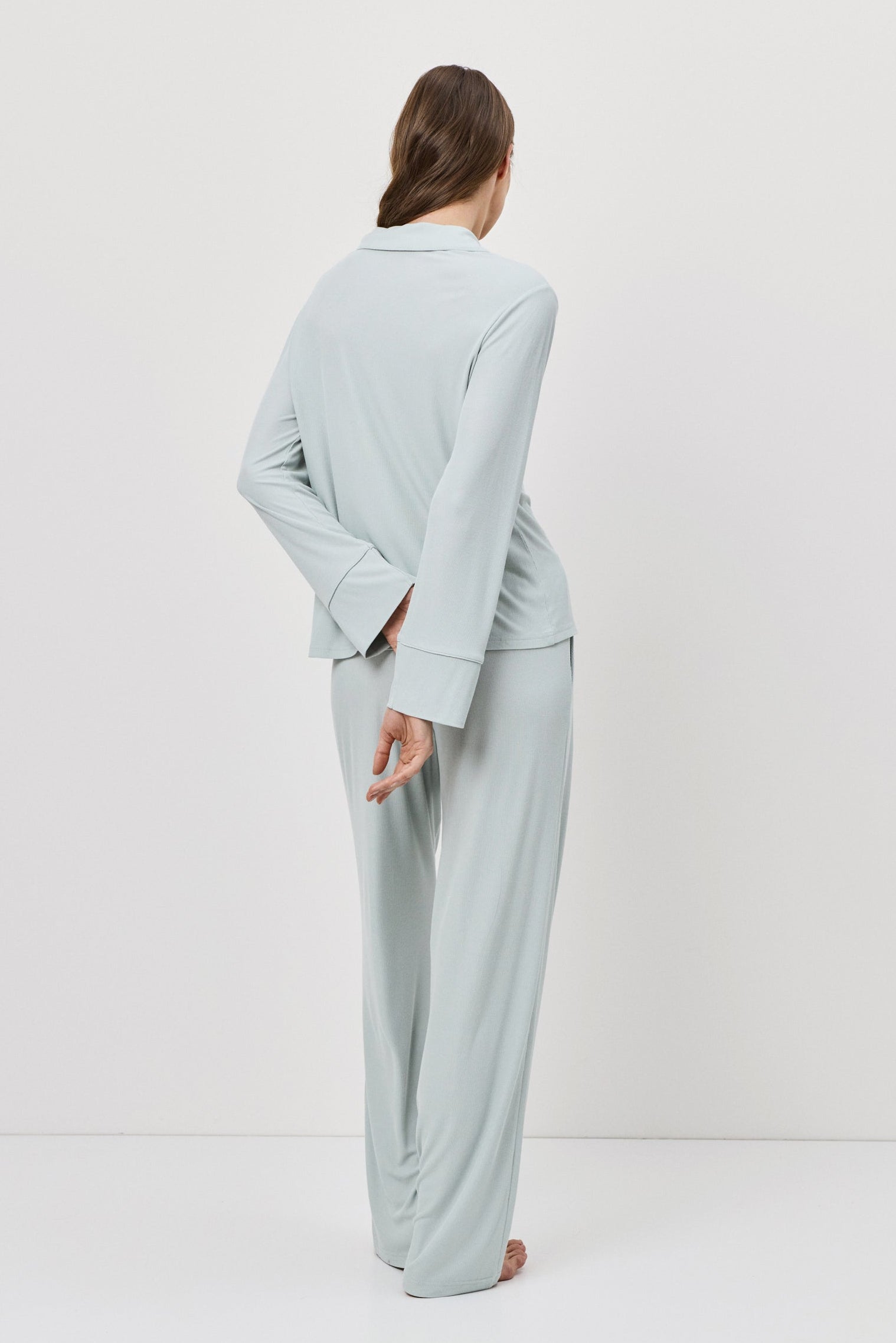 Woman wearing a light blue outfit standing against a white background