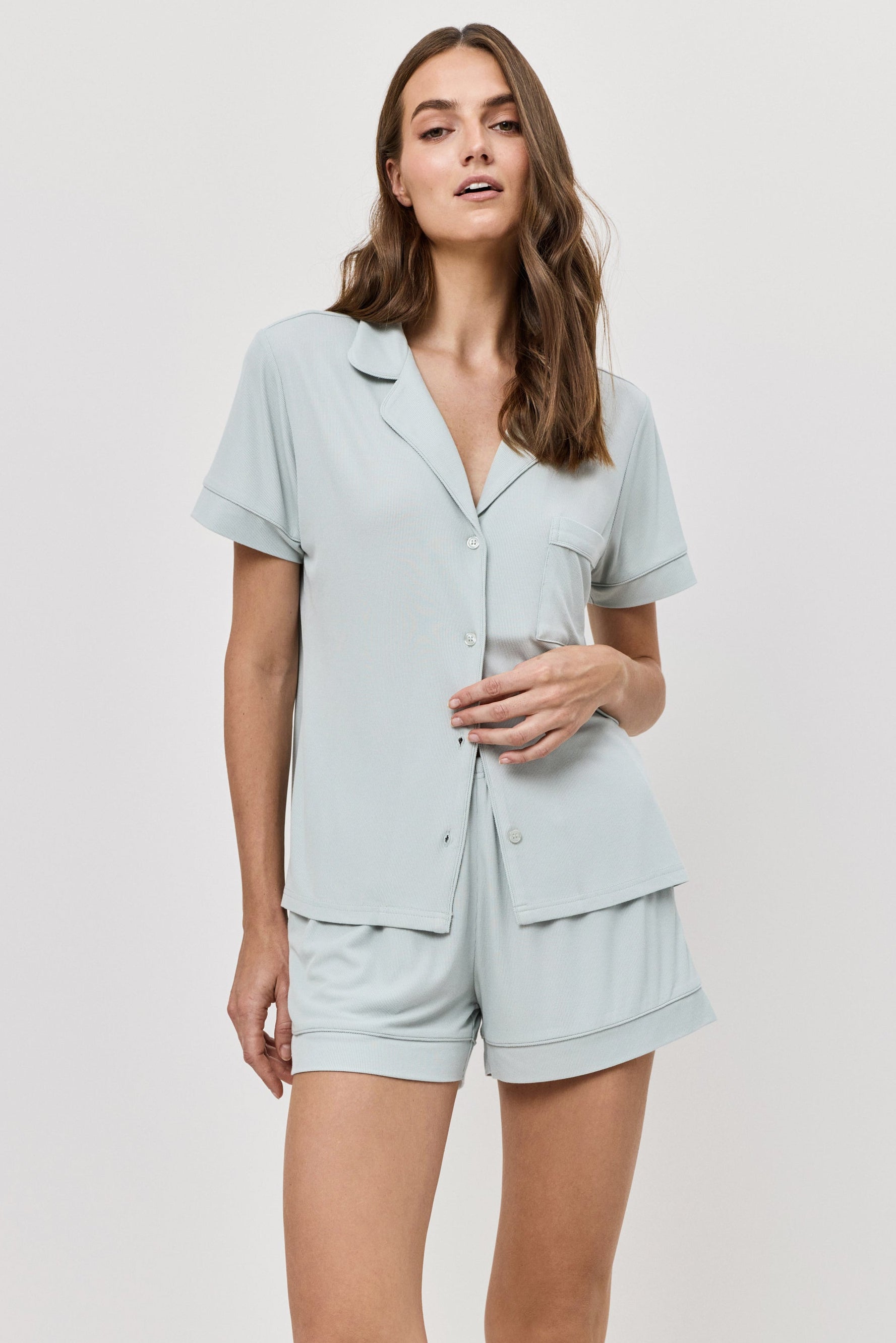 Woman wearing a light blue pajama set against a white background