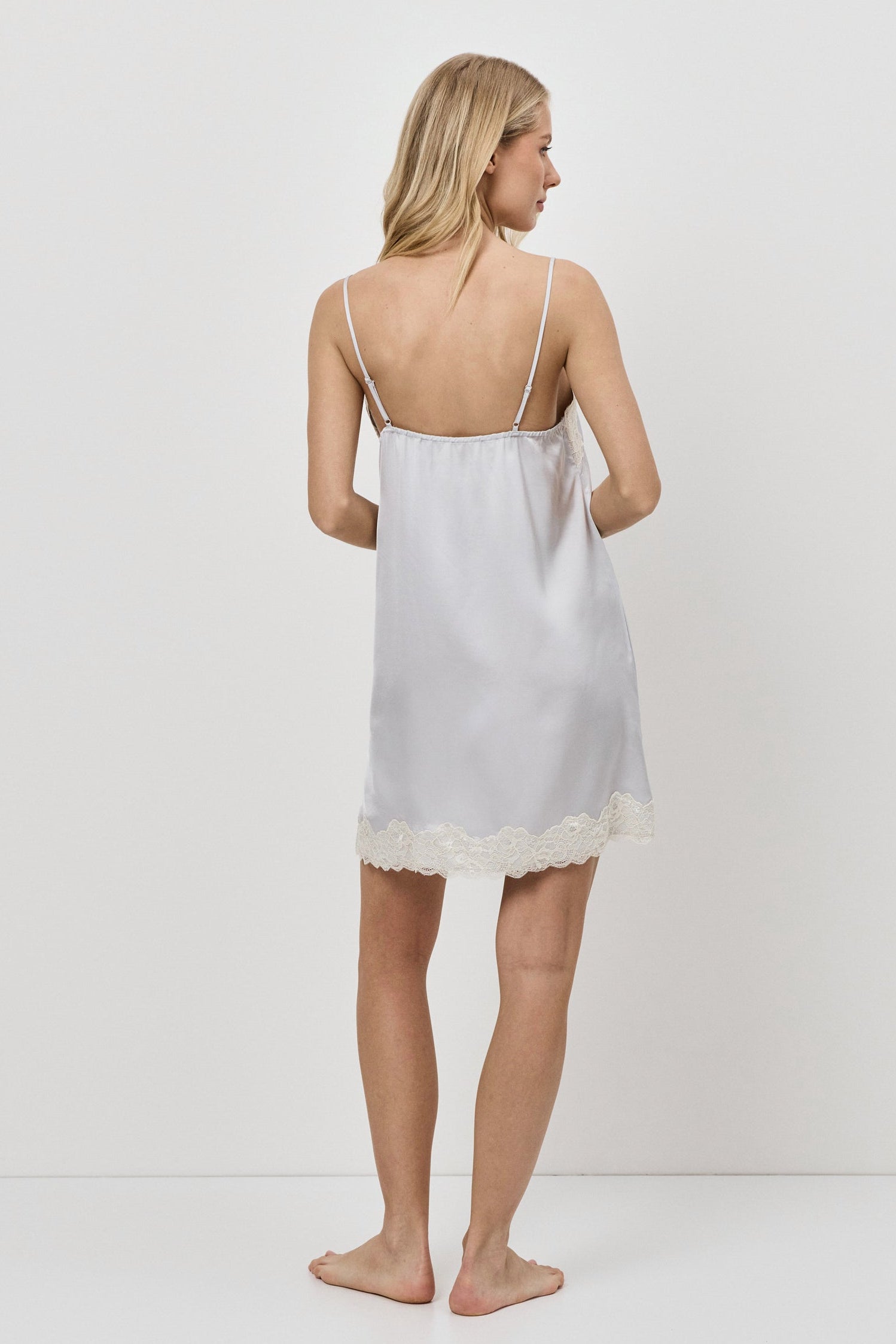 Woman wearing a gray nightdress against a plain background