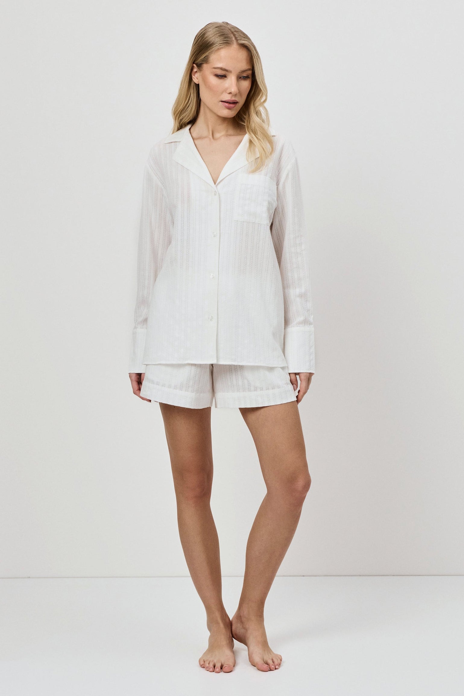 Woman wearing a white resort wear set on a plain background