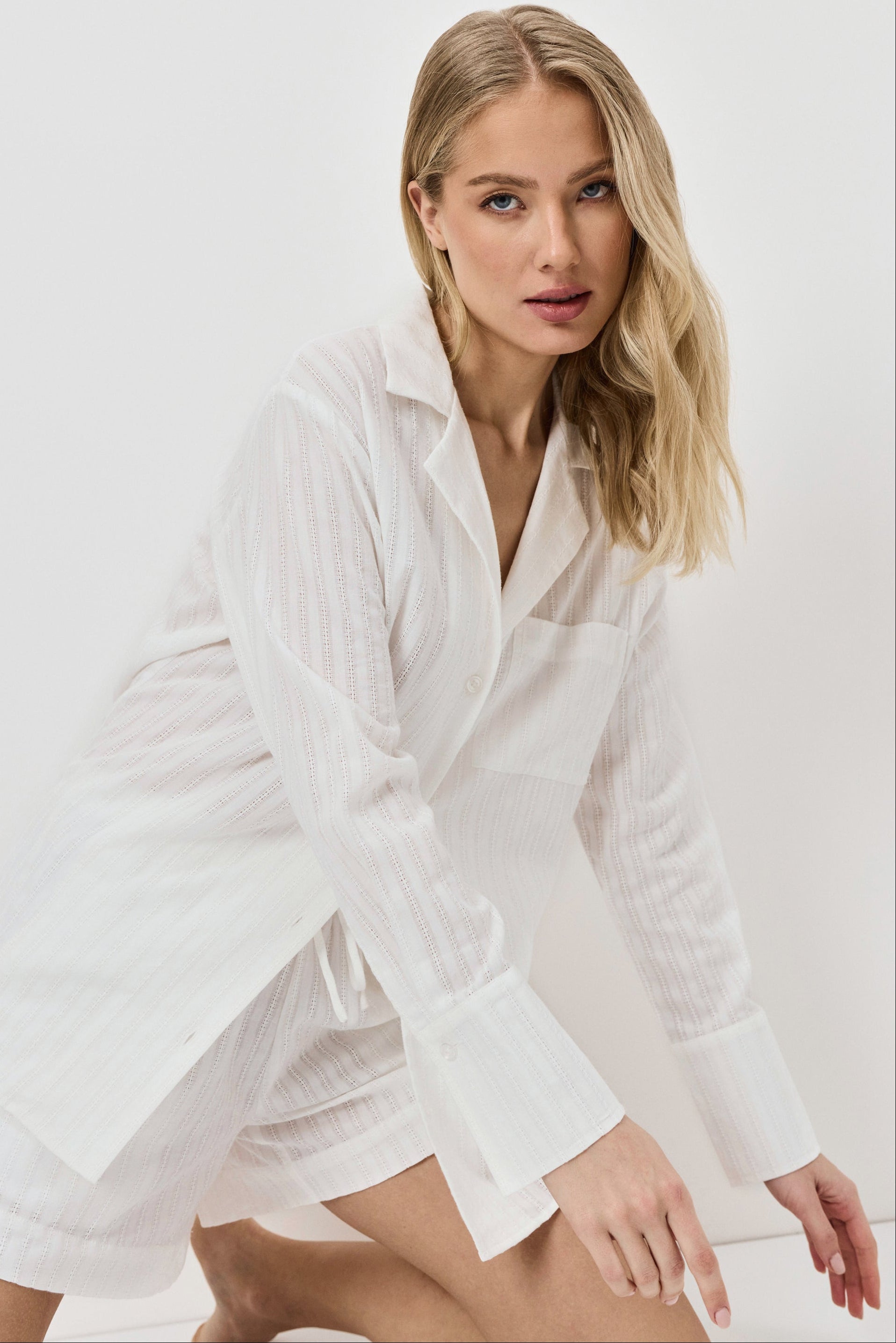 Woman wearing a white resort wear set against a plain background